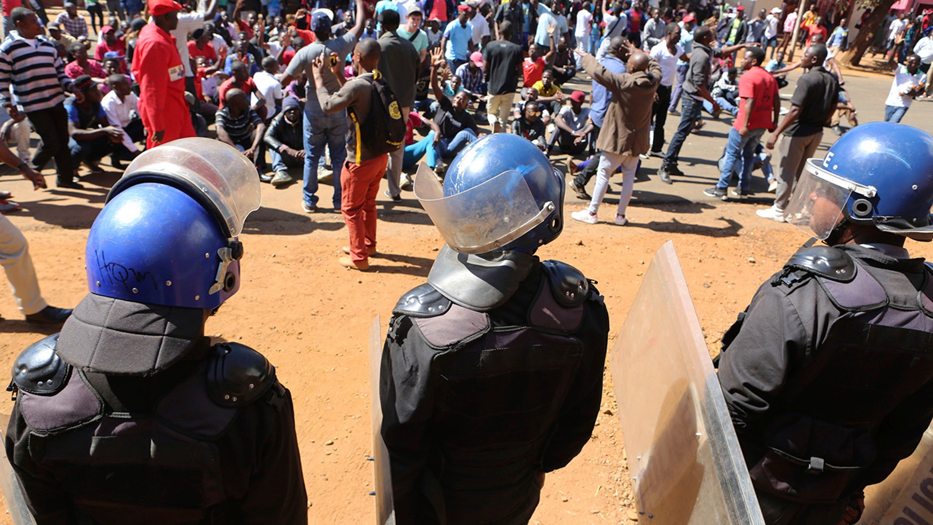 Police block dozens of opposition party supporters from entering the Zimbabwe Electoral Commission offices in Harare, Zimbabwe, Wednesday, Aug. 1, 2018. Zimbabwe's ruling party has won a majority of seats in Parliament, the electoral commission announced Wednesday, as the country braced for the first official results of the presidential election. (AP Photo/Tsvangirayi Mukwazhi)