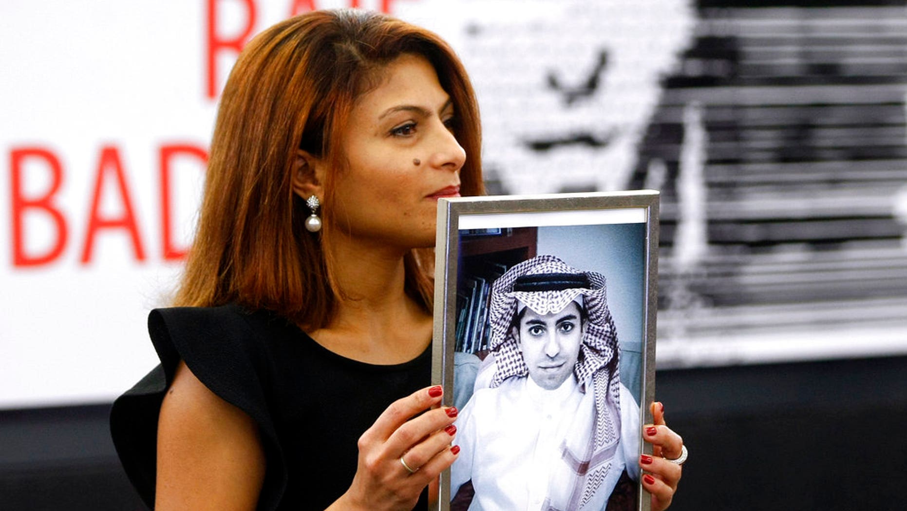 FILE - In this Dec, 16, 2015 file photo, Ensaf Haidar, wife of the jailed Saudi Arabian blogger Raif Badawi, shows a portrait of her husband as he is awarded the Sakharov Prize, in Strasbourg, France. Saudi Arabia has given Canada's ambassador 24 hours to leave the kingdom after Canada criticized the recent arrest of women's rights activists. Among the arrested activists is Samar Badawi, whose writer brother Raif Badawi was arrested in Saudi Arabia in 2012 and later sentenced to 1,000 lashes and 10 years in prison for insulting Islam while blogging. (AP Photo/Christian Lutz, File)