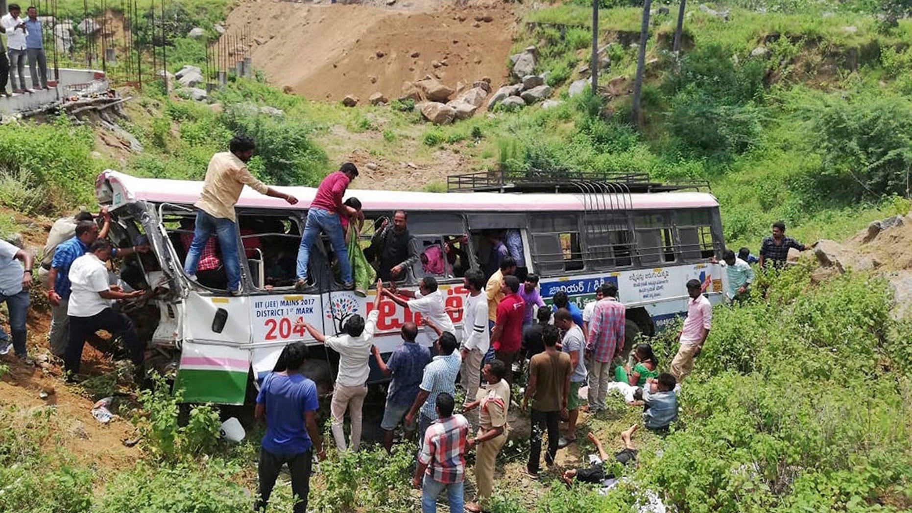 Rescuers pull out passengers from a bus that fell into a gorge in Jagtiyal district of Telangana, India, Tuesday, Sept. 11, 2018. A bus carrying pilgrims from a Hindu temple in the hills of south India plunged off a road Tuesday, killing more than 50 people including four children, officials said. (AP Photo)