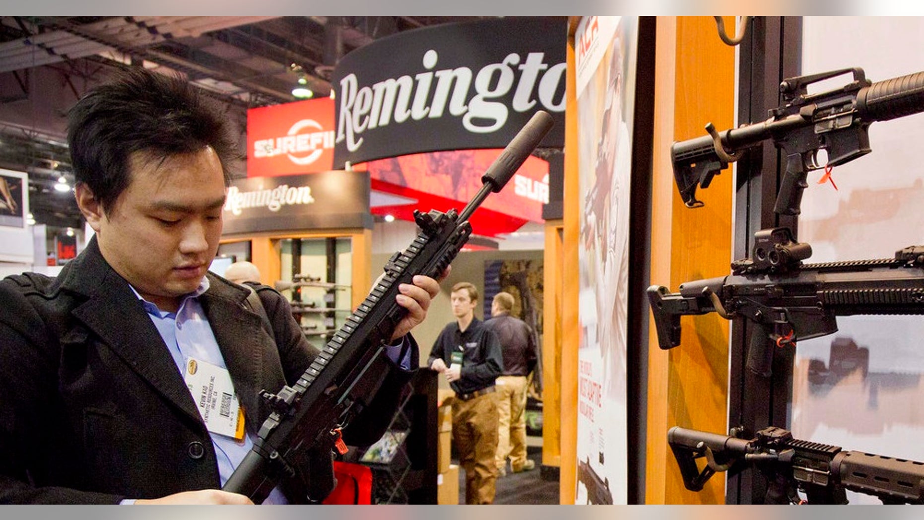 FILE- In this Jan. 15, 2013, file photo, accessories manufacturer Kevin Kao, of Irvine, Calif., examines a military grade Remington Adaptive Combat Rifle at the 35th annual SHOT Show in Las Vegas. A U.S. judge has struck down a nearly century-old California law that banned gun shops from advertising handguns on their premises. Judge Troy Nunley in Sacramento ruled Tuesday, Sept. 11, 2018, that the law violated the First Amendment. Nunley said the state failed to show that enforcing the law would prevent violence or suicides. The ruling came in a lawsuit filed in 2014 by several gun dealers who were fined by the state for handgun ads. The 1923 law banned any handgun ads at gun shops that were visible from outside the store. (AP Photo/Julie Jacobson, File)