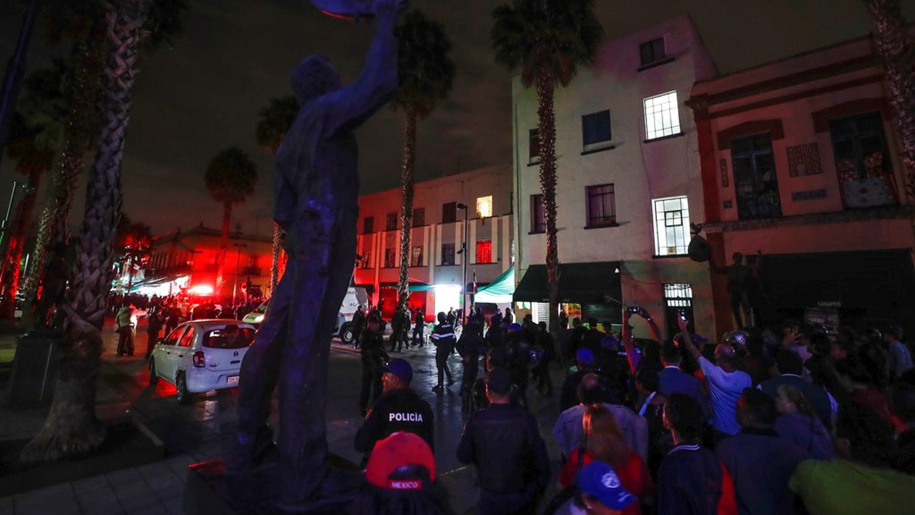 Curious onlookers gather on the perimeters of a crime scene after a shooting in Garibaldi Plaza in Mexico City.