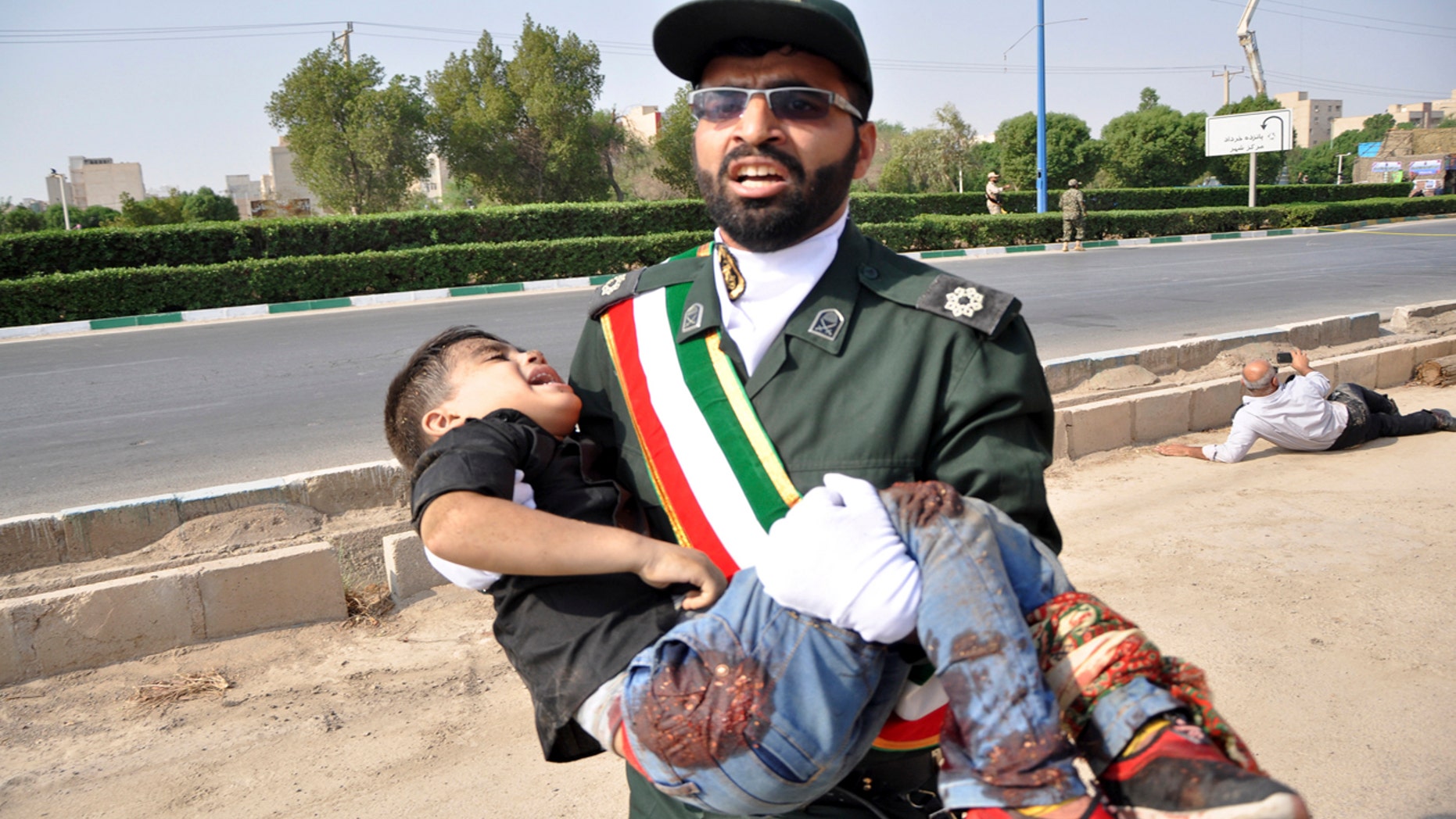 A Revolutionary Guard member carries a wounded boy after a shooting during a military parade marking the 38th anniversary of Iraq's 1980 invasion of Iran, in the southwestern city of Ahvaz, Iran, Saturday, Sept. 22, 2018.