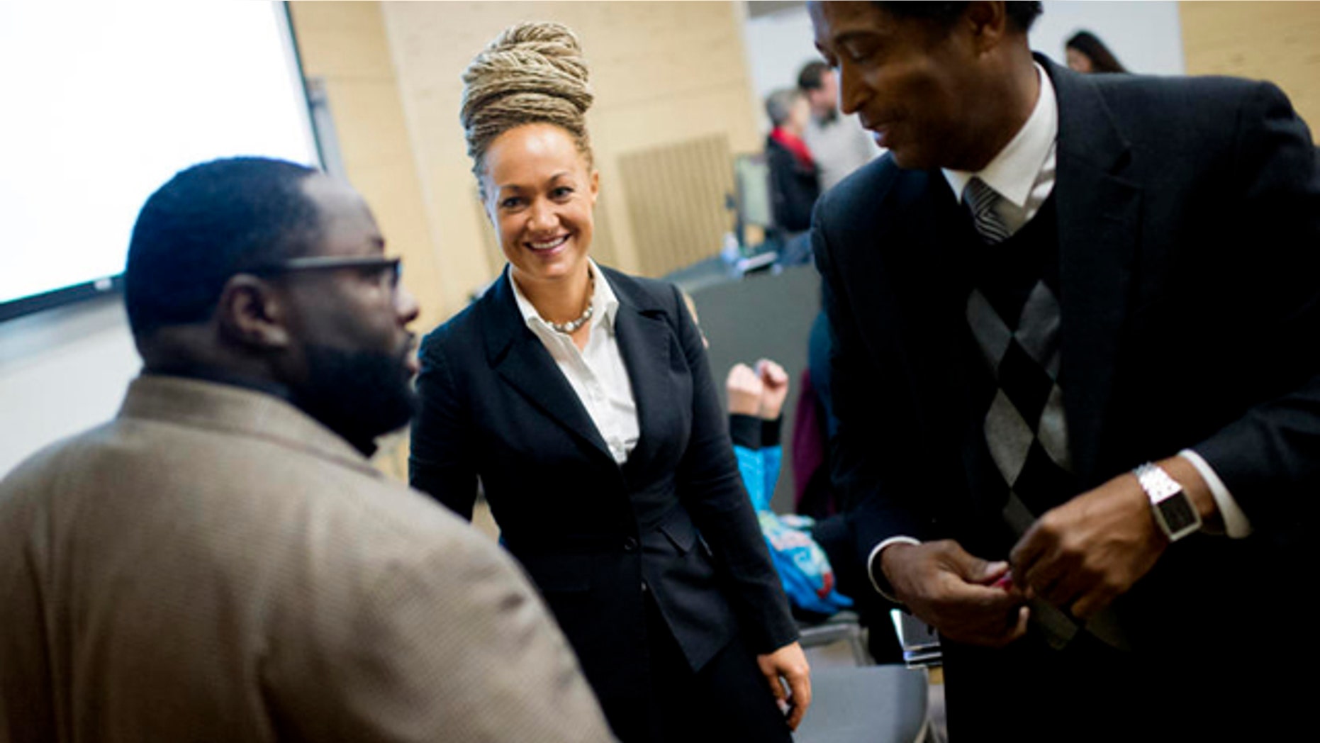 FILE- In this Friday, Jan. 16, 2015 file photo, Rachel Dolezal, Spokane's newly elected NAACP President, smiles as she meets with Joseph M. King of King's Consulting, left, and Dr. Scott Finnie, director and senior professor of EWU's Africana Education Program before the start of a Black Lives Matter Teach-In on Public Safety and Criminal Justice at EWU in Cheney, Wash. (Tyler Tjomsland/The Spokesman-Review via AP, File) COEUR D'ALENE PRESS OUT