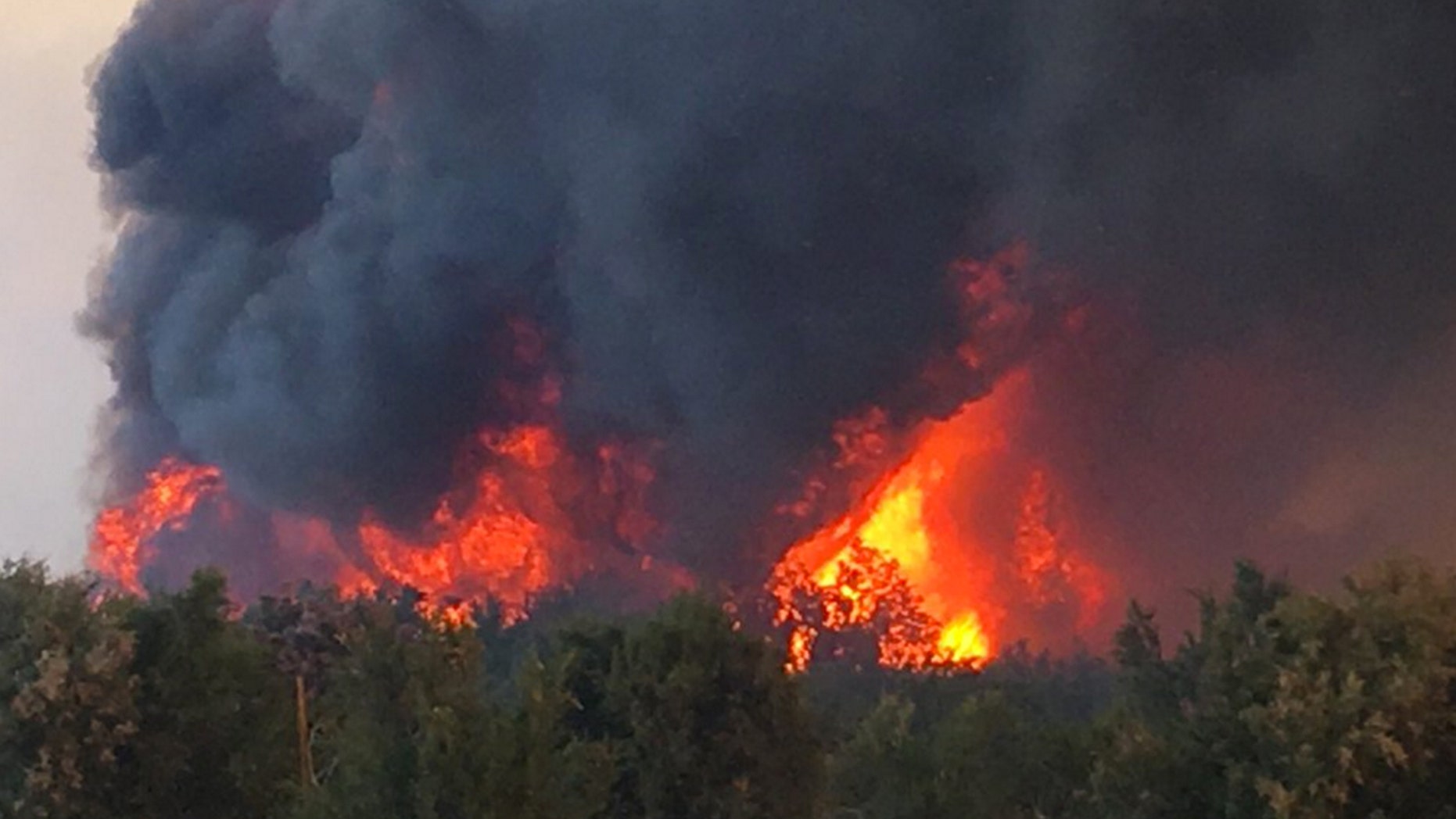 This photo provided by the San Bernardino County Fire Department shows a flareup of a wildfire that started in western Arizona and jumped the Colorado River into California, near Needles, Calif., Wednesday, April 6, 2016. Two mobile home parks, Pirate's Cove and Park Moabi RV parks in the Mojave Desert south of Needles, were evacuated as firefighters on both sides of the river worked to surround the flames.(San Bernardino County Fire Department via AP) MANDATORY CREDIT