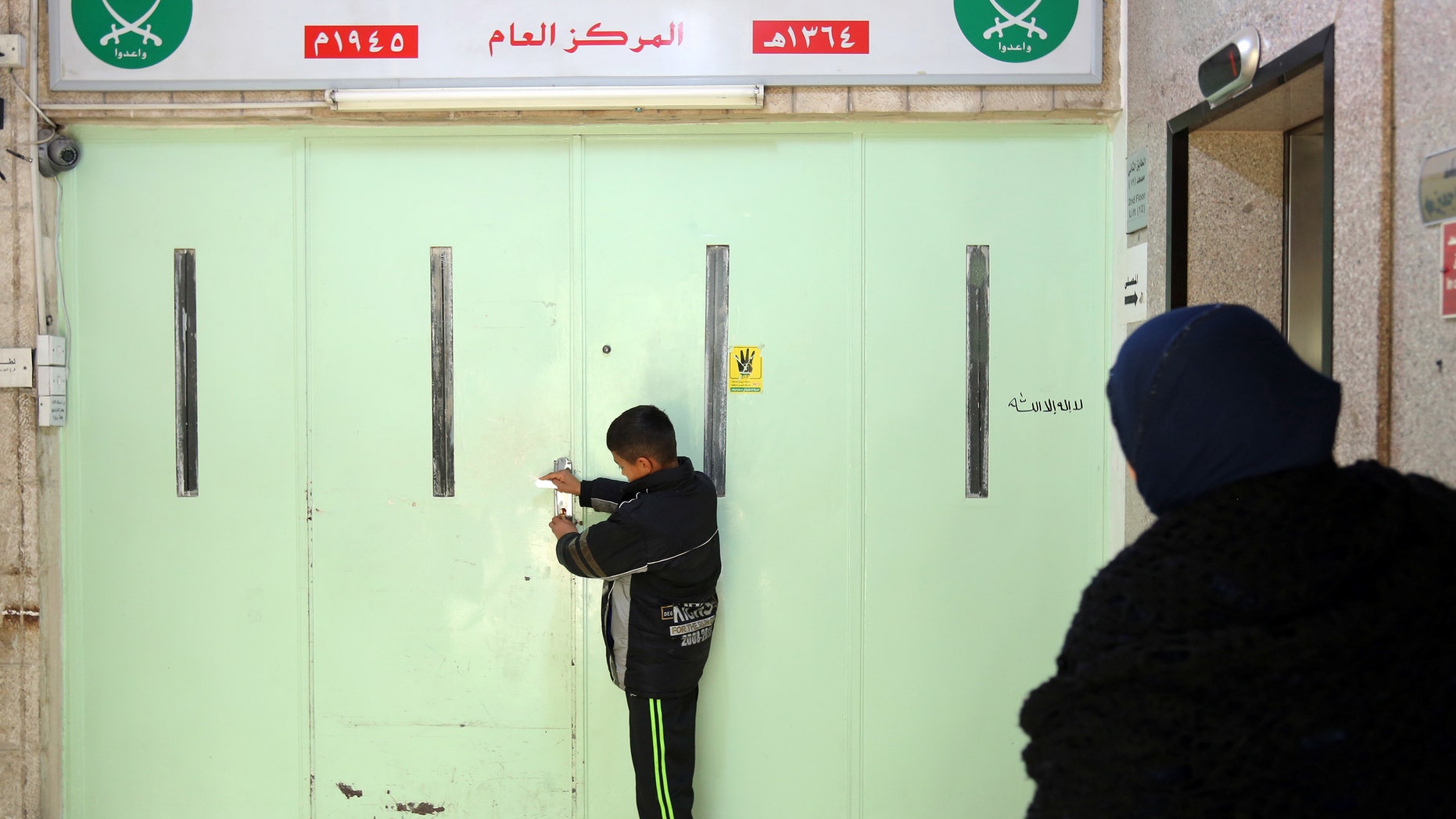 A boy stands at the main entrance of the original Muslim Brotherhood office, sealed with wax.