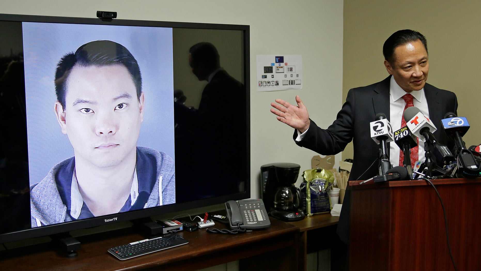 San Francisco Public Defender Jeff Adachi gestures while standing beside a picture of police officer Jason Lai, who resigned earlier in April.