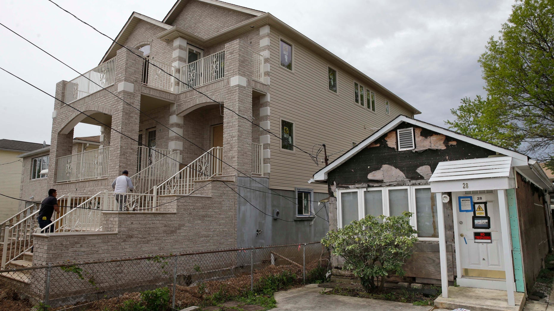 A house up for auction, right, sits next to a rebuilt and raised home in the New Dorp Beach section of New York's Staten Island.