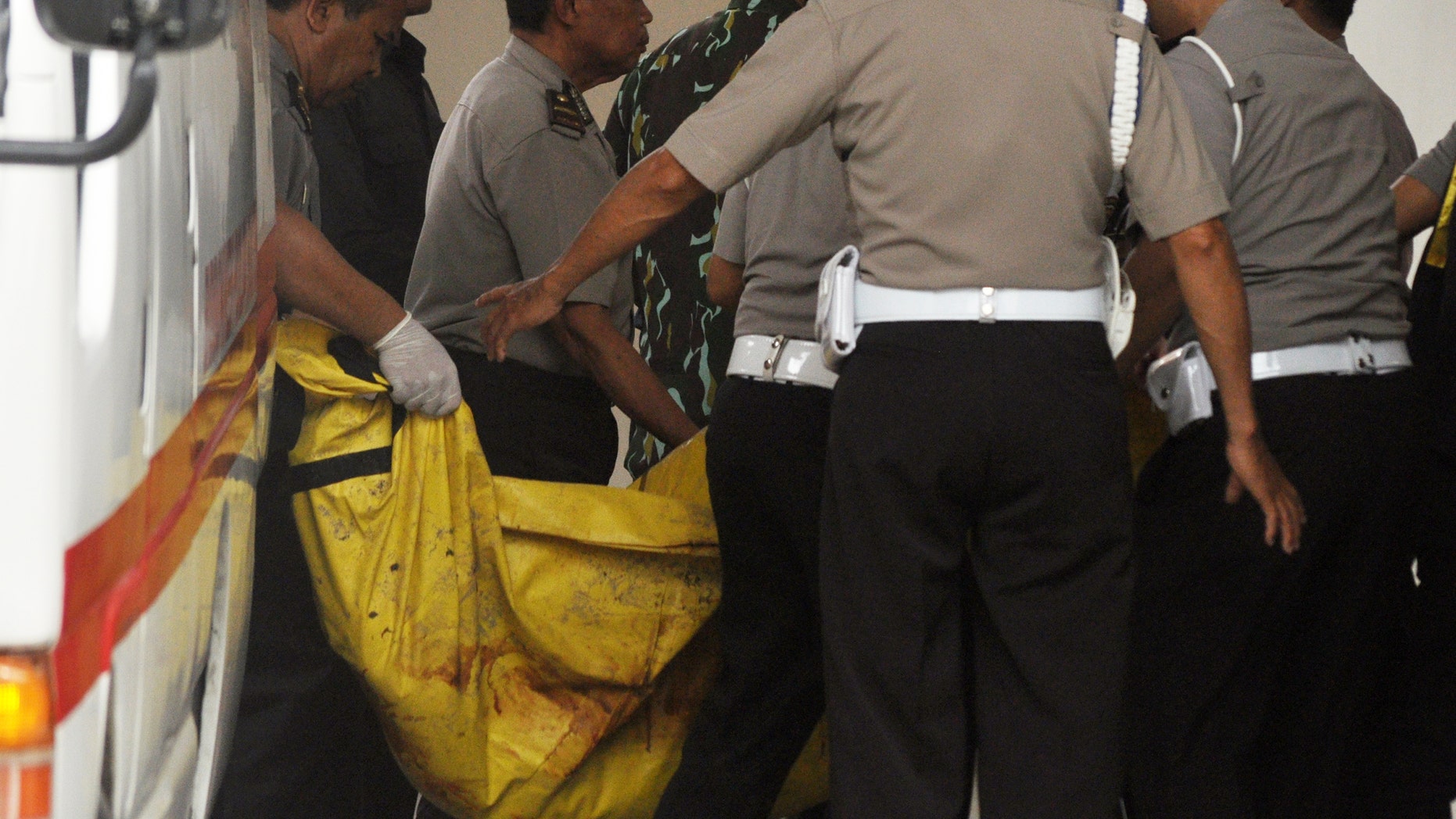 Indonesian police officers arriving at a hospital carry one of the two bodies of militants killed by Indonesian security forces.
