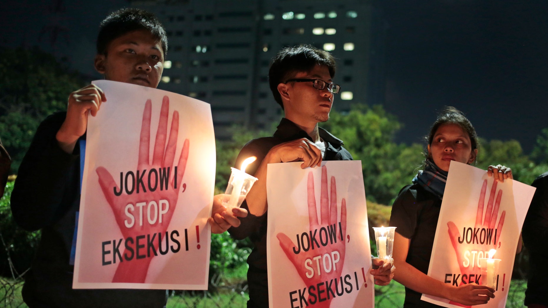 Activists hold posters which read "Jokowi, stop the executions!" during a vigil outside the presidential palace in Jakart. "Jokowi" is the popular nickname of Indonesian President Joko Widodo.