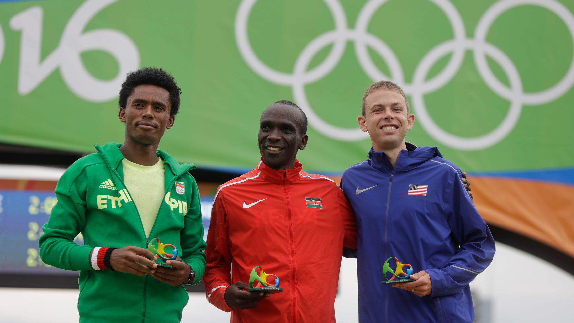 Kenyan gold medalist Eliud Kipchoge, center, celebrates on the podium flanked by Ethiopia's Feyisa Lilesa, left, who won silver, and Galen Rupp, who took bronze in the men's marathon.
