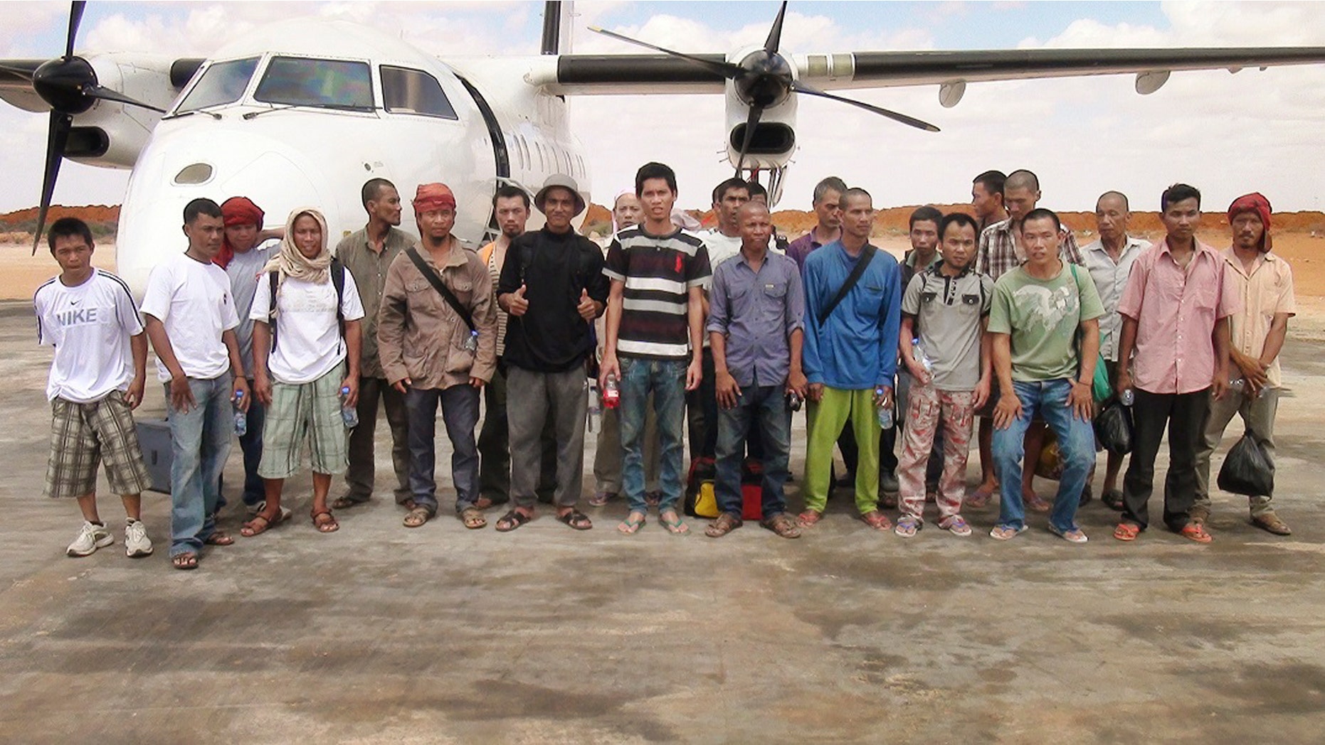 Sailors standing for a group photograph as they prepare to board an airplane after a Somali pirate said they were released.