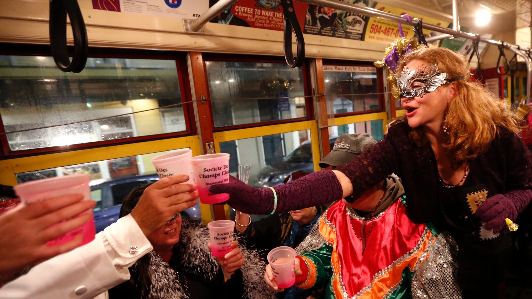 Members of the "Societe des Champs Elysee" toast as they ride the Rampart-St. Claude street car line, which just opened last fall, to commemorate the official start of Mardi Gras season, in New Orleans.
