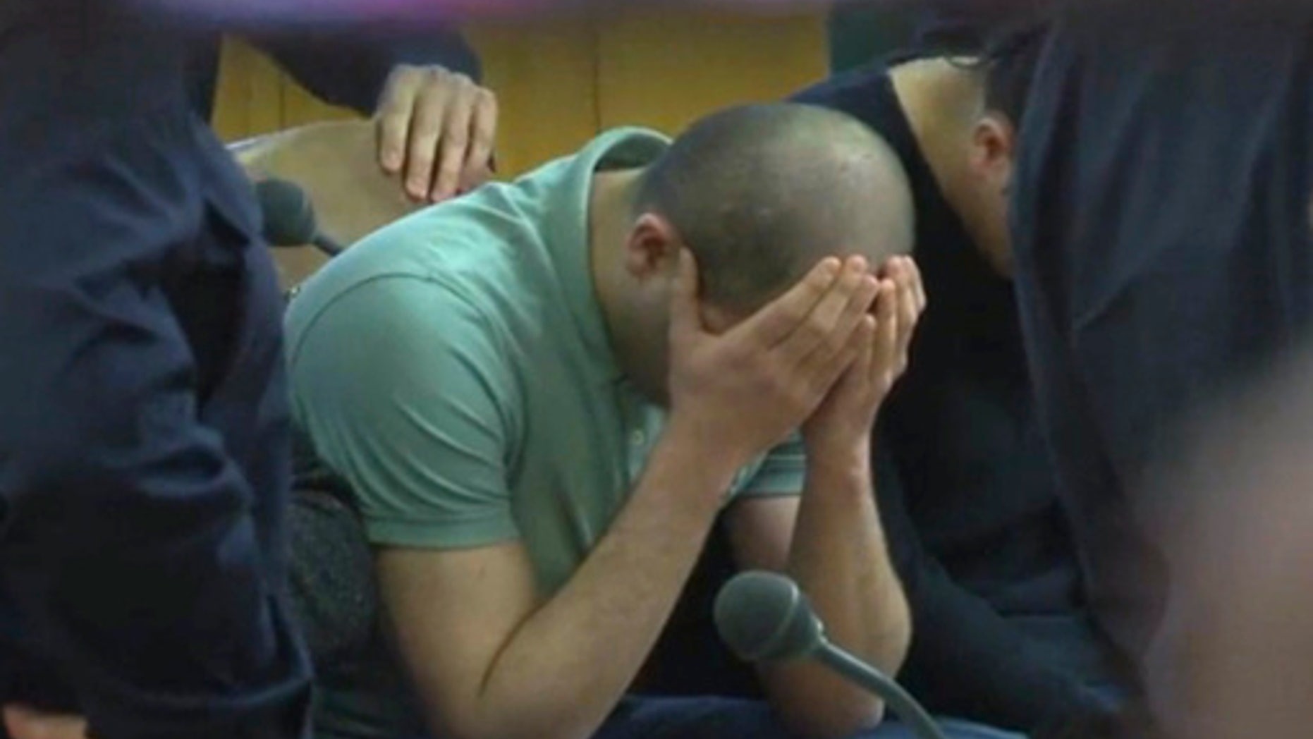 A defendant covers his face at the beginning of the trial.