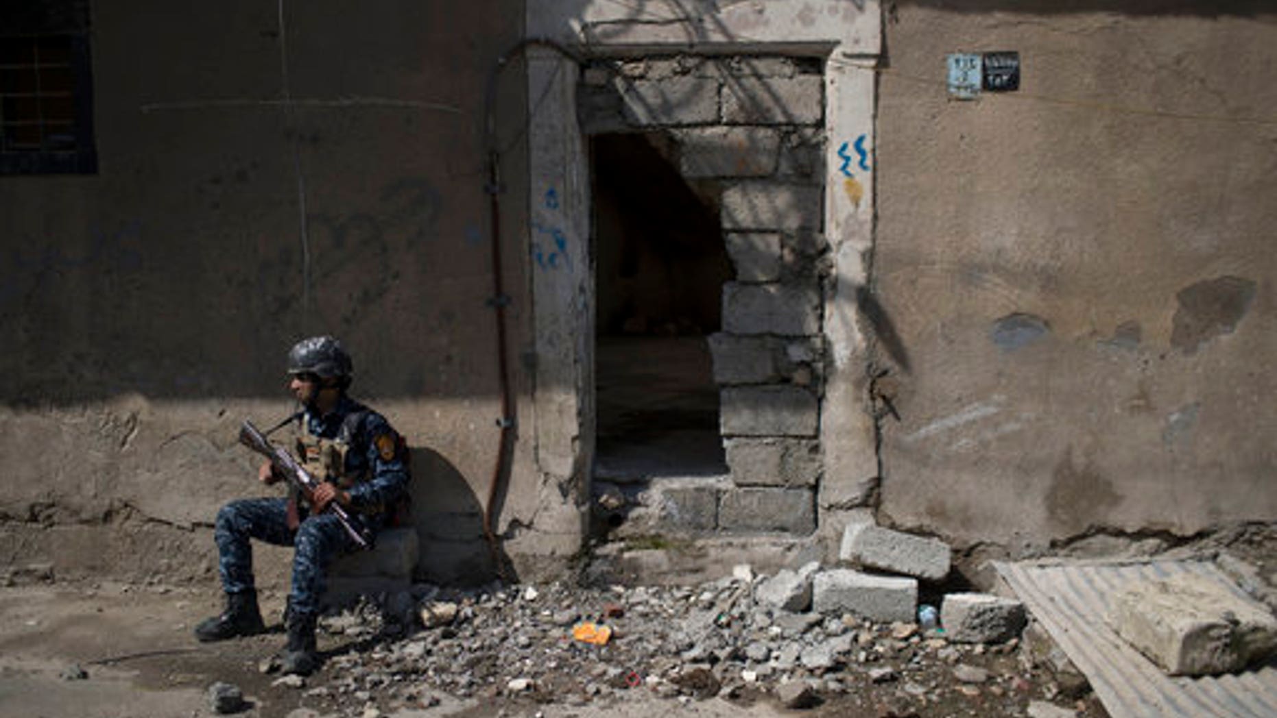 A federal policeman takes a break from inspecting houses during fighting against Islamic State militants on the western side of Mosul on Wednesday.