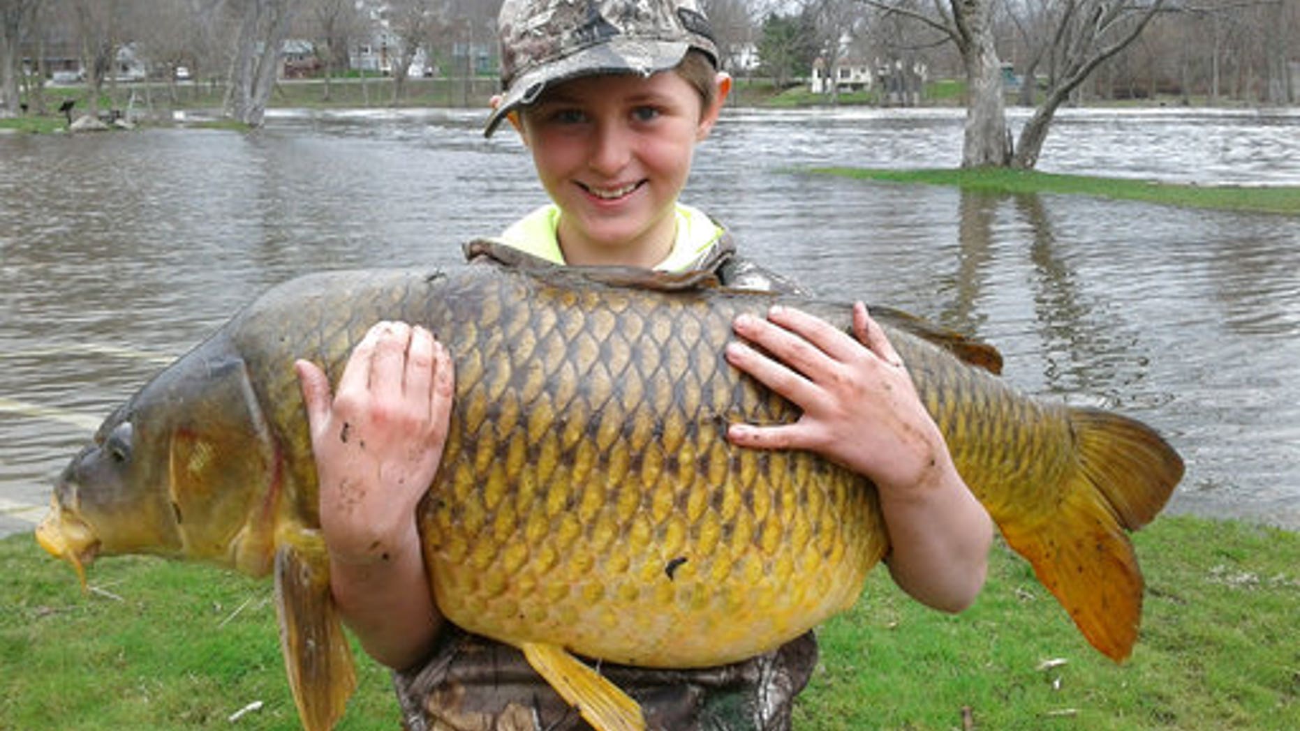 This April 22, 2017 photo released by John Stokes shows Stokes' son Chase, then 10, holding a giant carp, weighing 33.25 pounds, in Ferrisburgh, Vt. The Vermont Fish & Wildlife Department made the record official a few weeks ago, stating that the fish was a quarter-pound bigger than the previous record holder. (John Stokes via AP)
