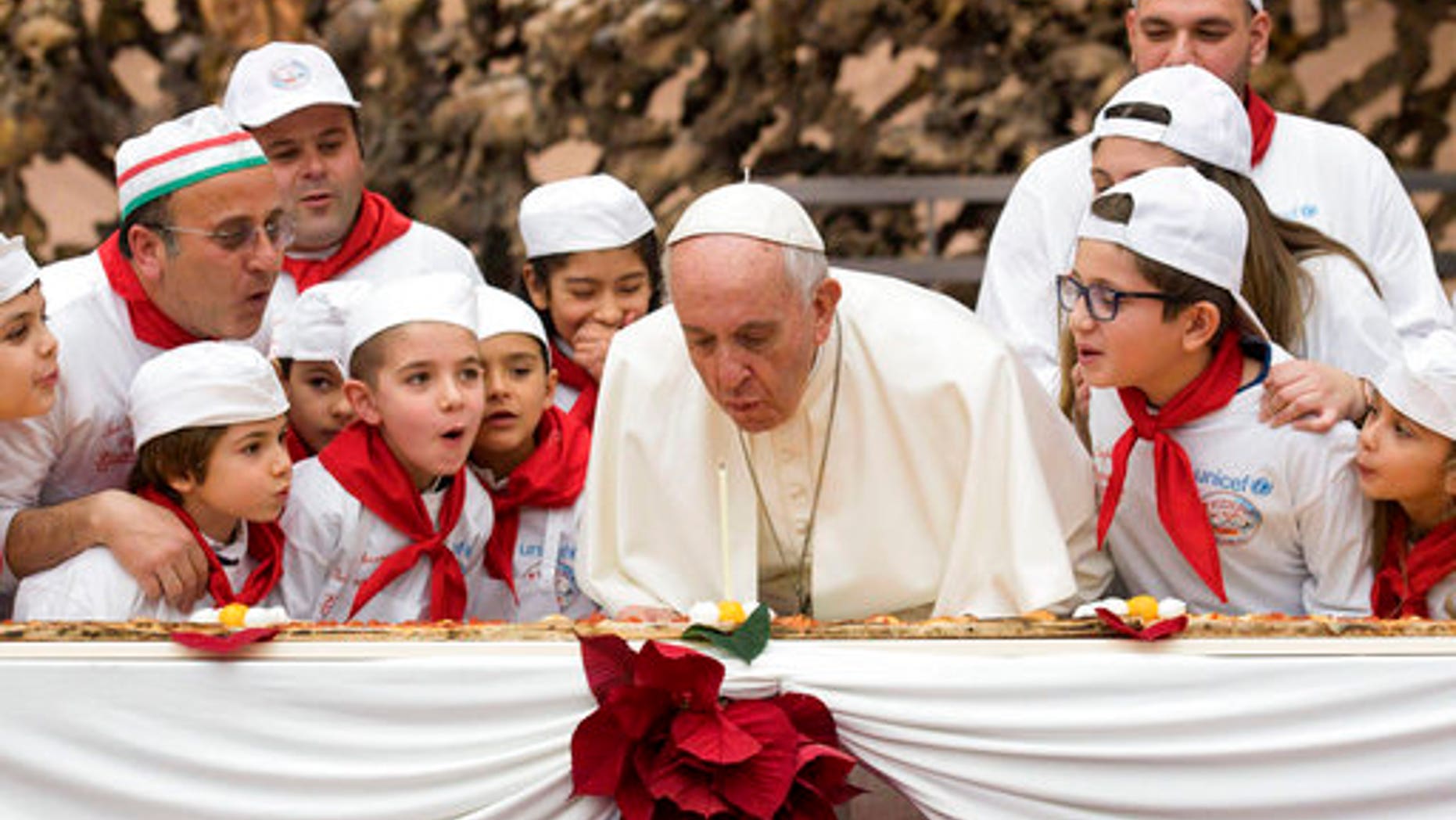 Pope Francis blows out a candle on pizza to celebrate his 81st birthday during a private audience with children at the Vatican.