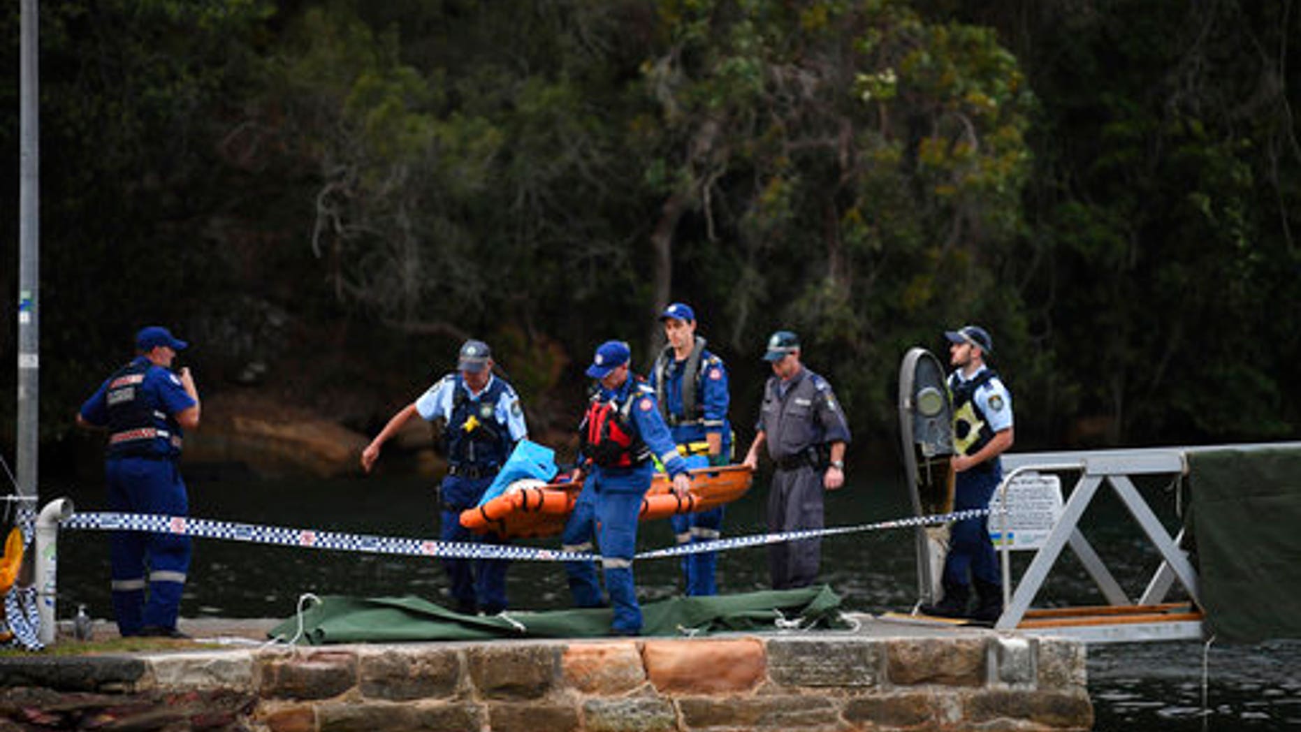 Emergency workers carry to shore what is believed to be a body and debris from a seaplane that crashed into the Hawkesbury River, north of Sydney, Australia.
