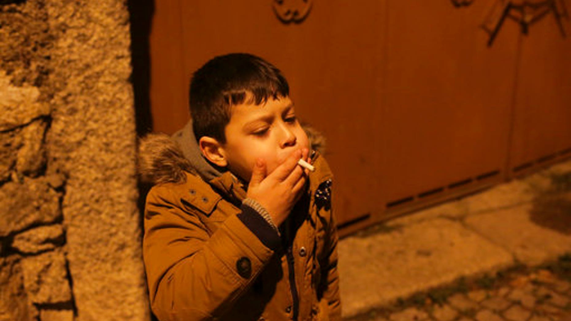 A young boy smokes in the street in the village of Vale de Salgueiro, northern Portugal, during the local Kings' Feast Friday, Jan. 5, 2018.