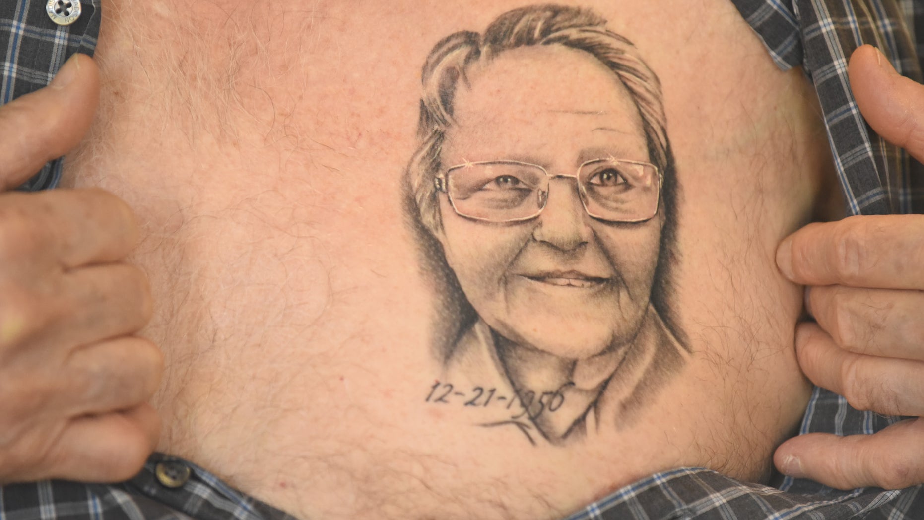 Arthur Burch shows a portrait of his wife's face tattooed on his chest.