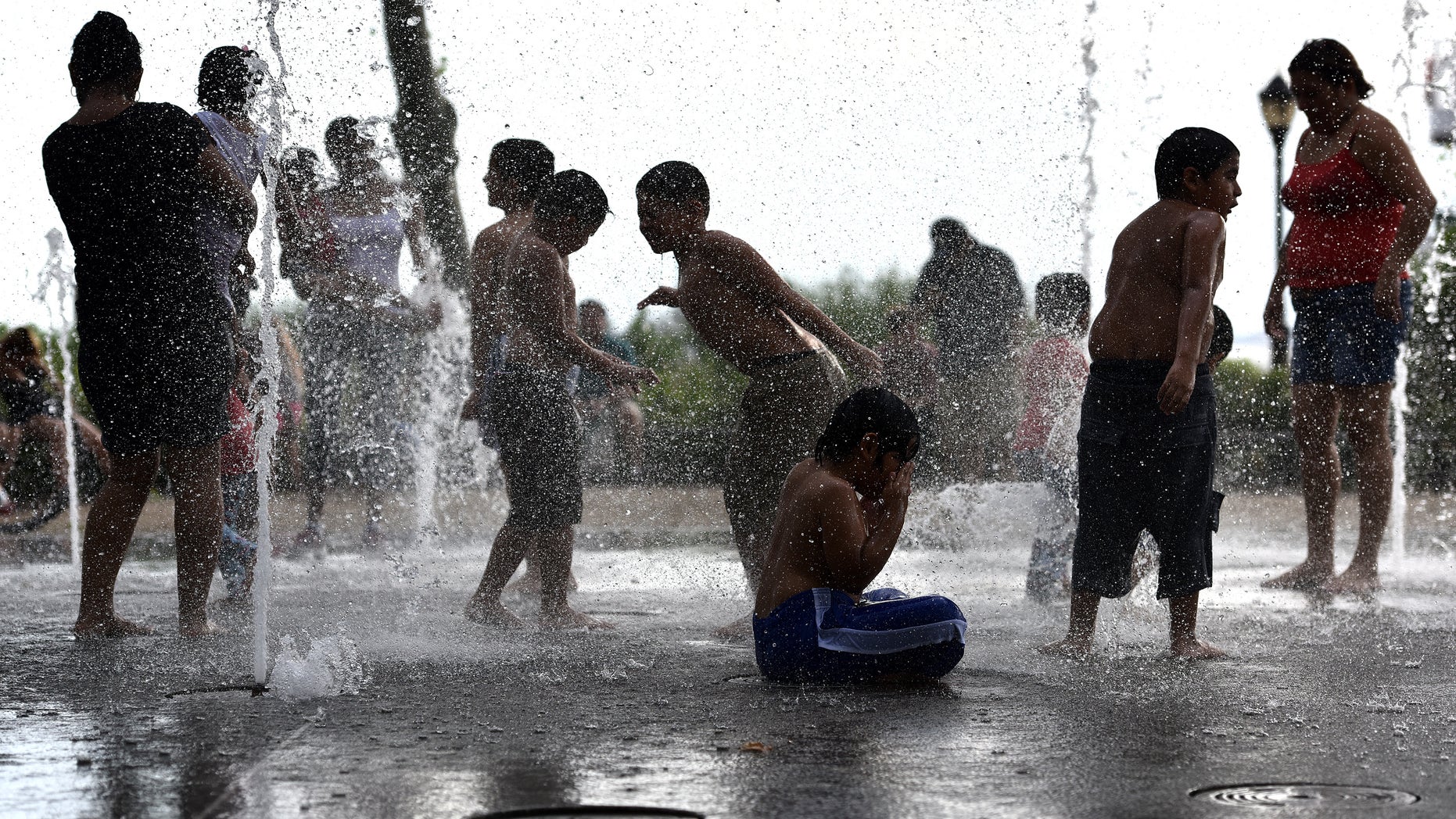 Children play in water jets of Battery Bosque Park fountain over the weekend during the heat wave.