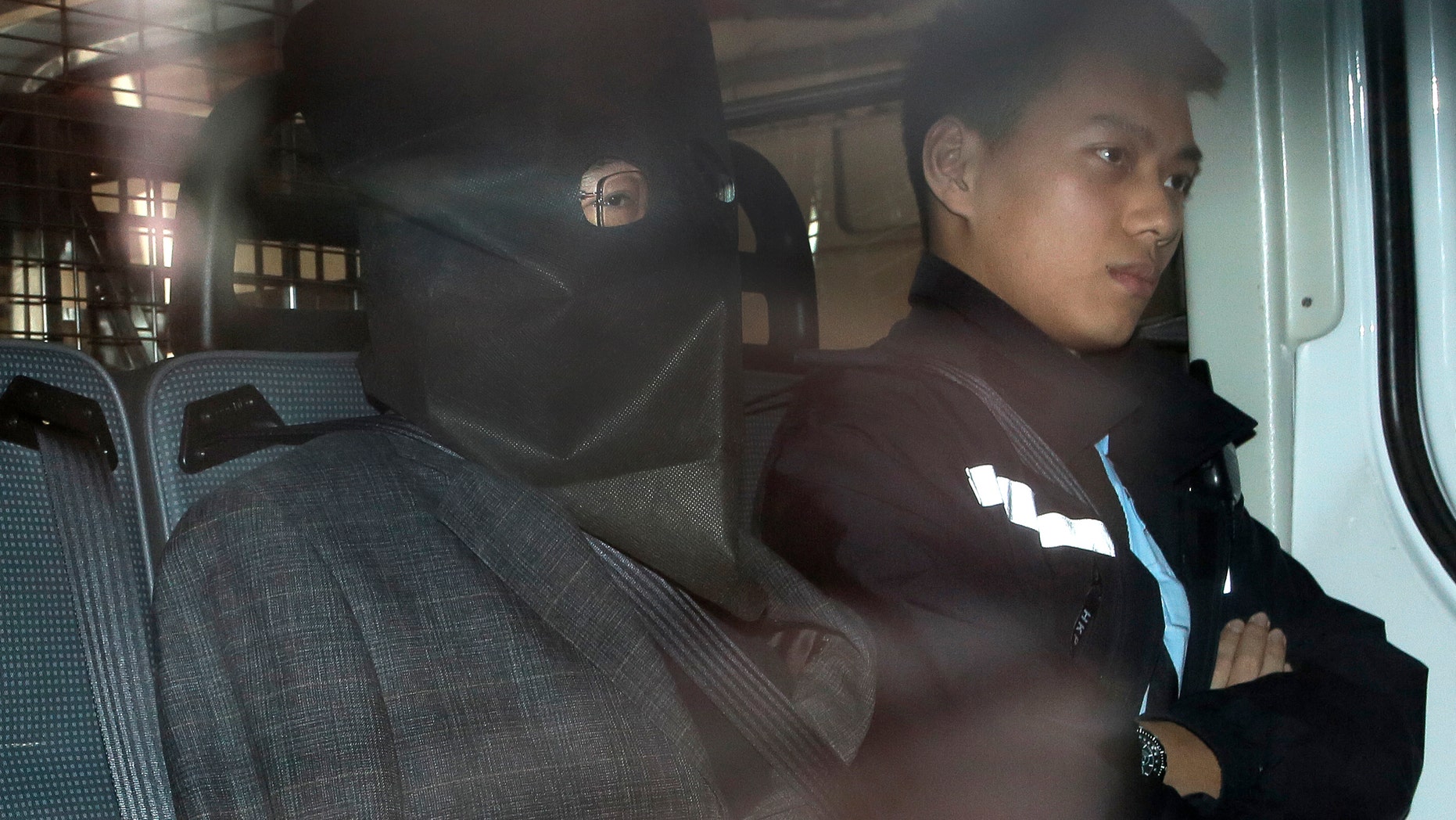 Shi Deyun, left, escorted by a police officer in a police van, arrives at a magistrate court in Hong Kong in January.