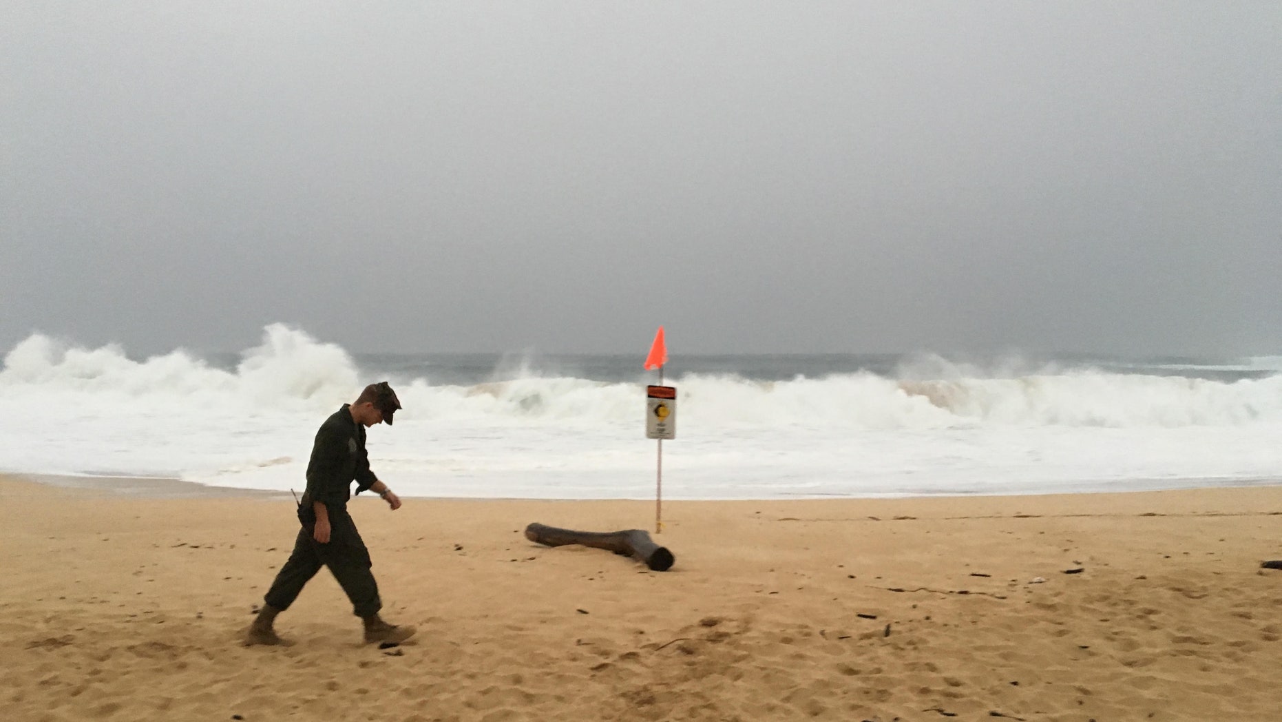 A U.S. Marine walks on the beach at Waimea Bay near Haleiwa, Hawaii, where two military helicopters crashed into the ocean about 2 miles offshore.