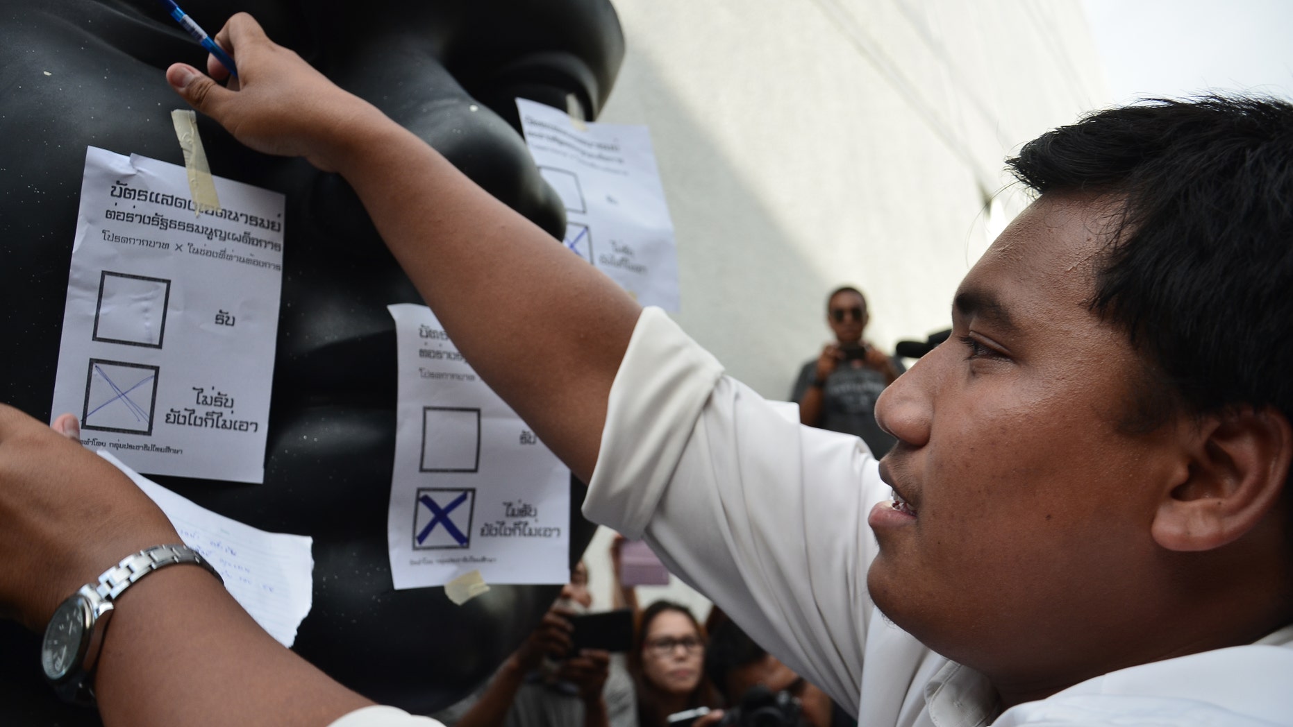 Sirawith Seritiwat sticks a mock ballot with 'NO' selected on a statue during a protest against a military-backed draft constitution, in September 2015.
