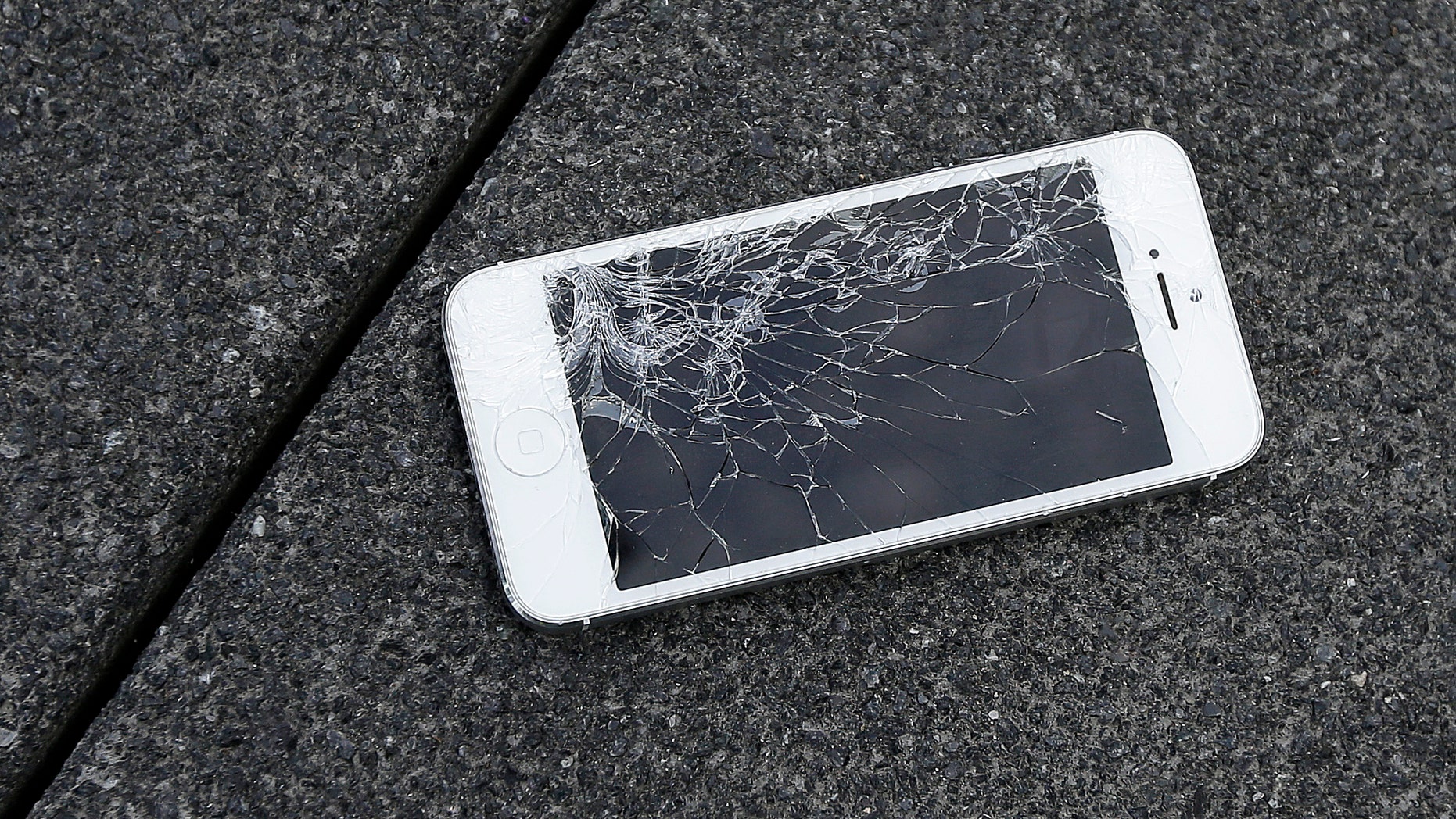 FILE - This Aug. 26, 2015 photo shows an Apple iPhone with a cracked screen after a drop test from the DropBot, a robot used to measure the sustainability of a phone to dropping, at the offices of SquareTrade in San Francisco. Apple for the first time is accepting banged up iPhones as a trade-in from those wanting to upgrade. (AP Photo/Ben Margot)