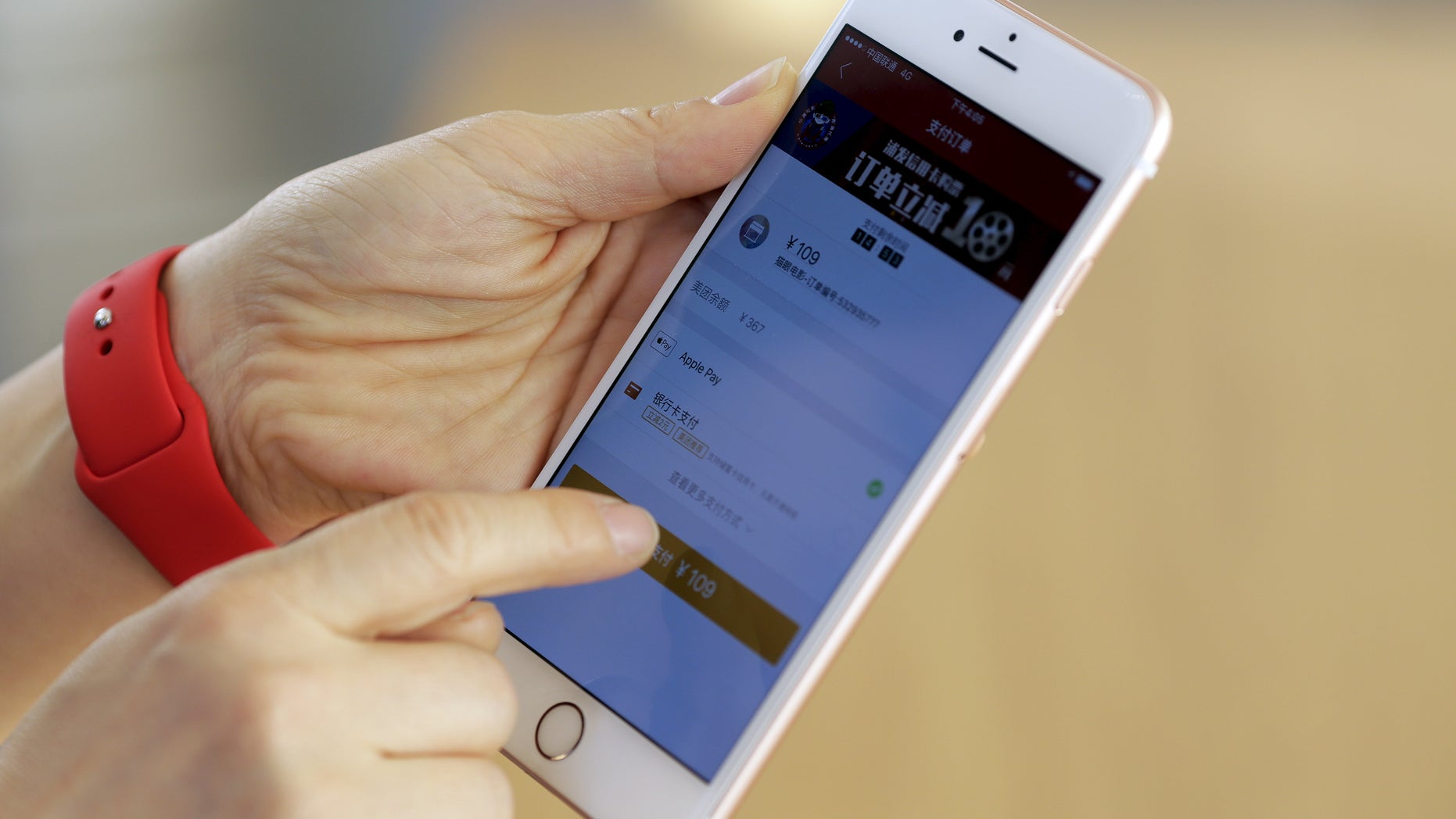 An employee uses an Apple iPhone to demonstrate to reporters how to pay using the Apple Pay service at an Apple store in Beijing, China, February 17, 2016. (REUTERS/Damir Sagolj)