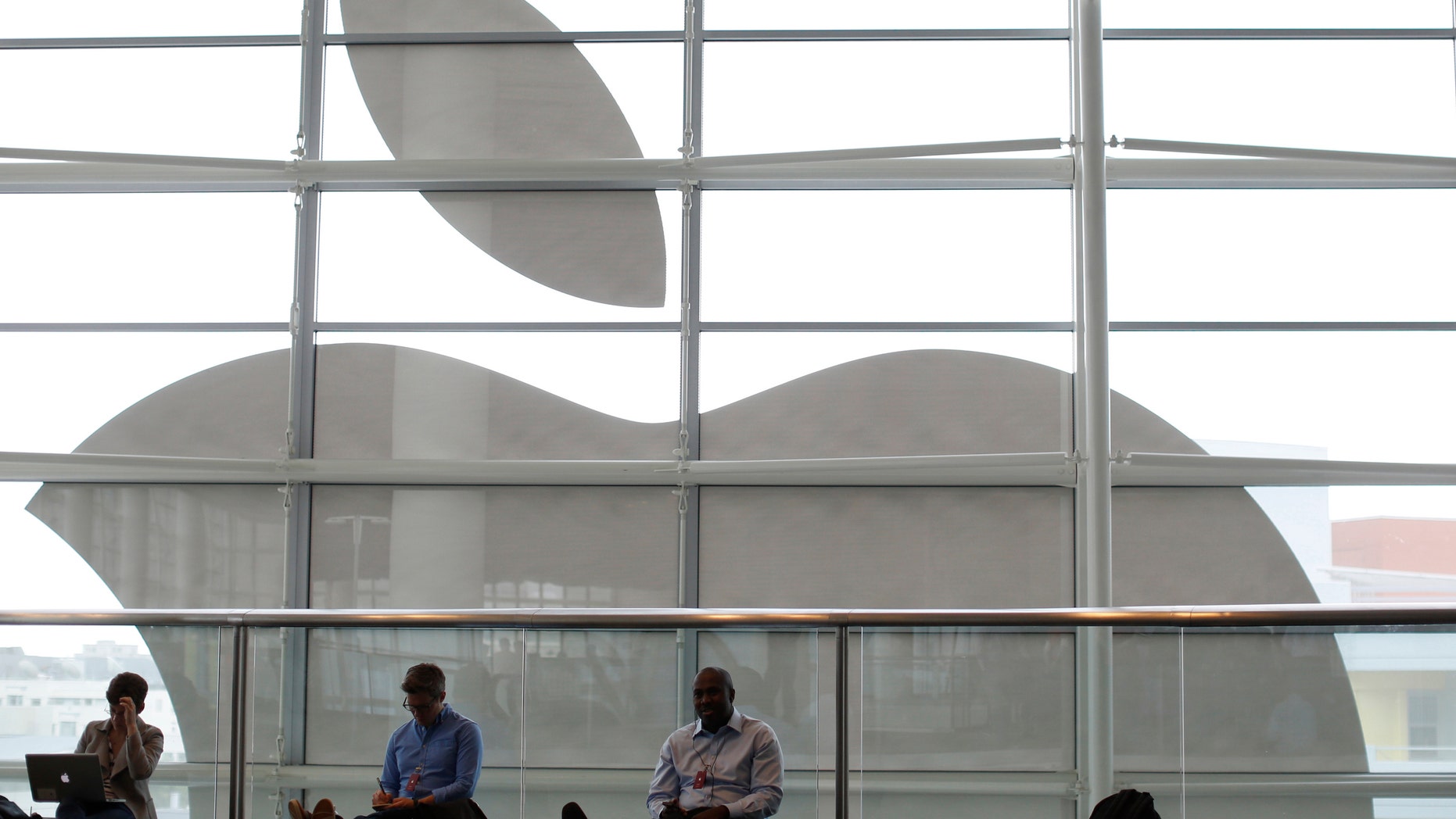 File photo - Attendees sit in front of an Apple logo at the Apple Worldwide Developers Conference (WWDC) 2013 in San Francisco, Calif. June 10, 2013. (REUTERS/Stephen Lam)