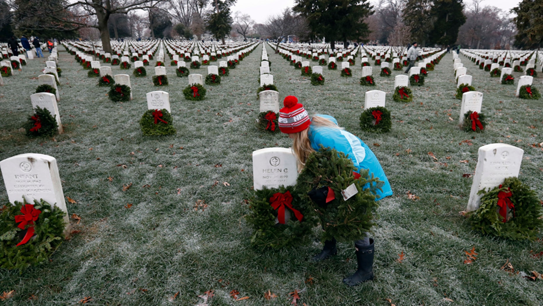 Madeline Espinosa, 11, of Bethesda, Md., places a wreath at a grave as part of Wreaths Across America at Arlington National Cemetery, Saturday, Dec. 17, 2016 in Arlington, Va. Organizers estimate more than 245,000 wreaths were placed at graves throughout the cemetery. (AP Photo/Alex Brandon)
