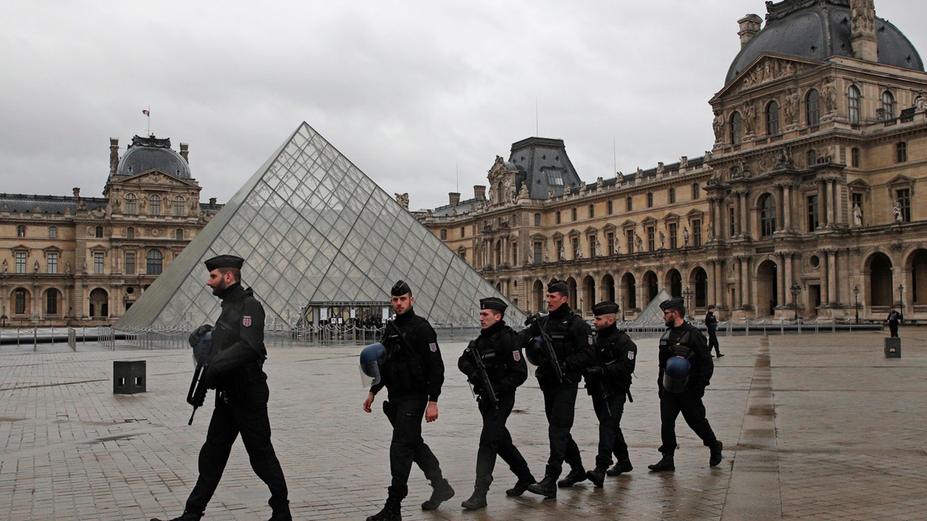 Armed police officers patrol in the courtyard of the Louvre museum near where a soldier opened fire after he was attacked in Paris, Friday, Feb. 3, 2017.