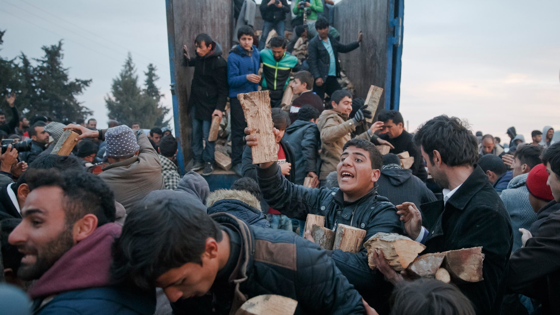 Migrants mob a truck bringing donated firewood at the northern Greek border station of Idomeni.