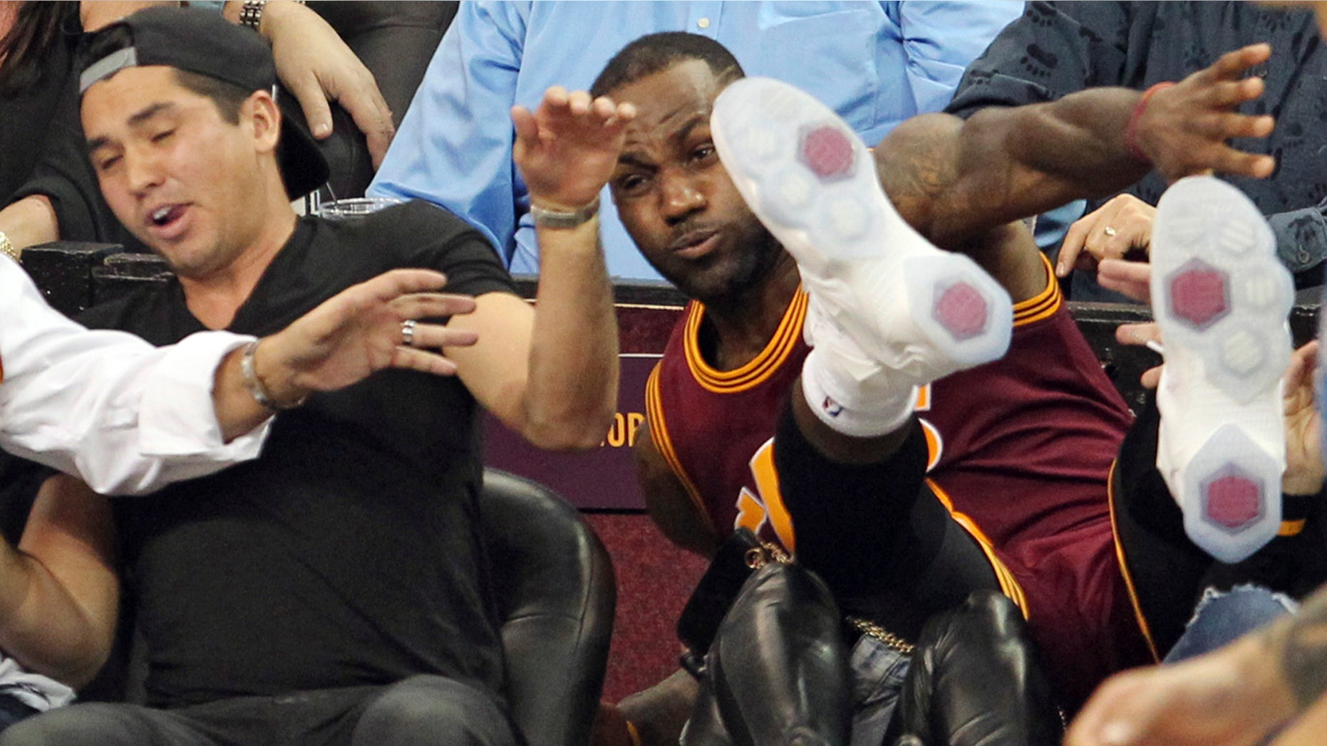 Dec. 17, 2015: Cleveland Cavaliers' LeBron James falls into Ellie Day, wife of PGA Tour golf player Jason Day, at left, during the second half of an NBA basketball game against the Oklahoma City Thunder in Cleveland. (John Kuntz/The Plain Dealer via AP)