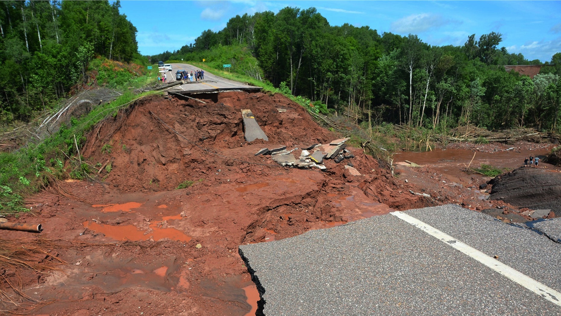 July 12, 2016: People observe part of Wisconsin Highway 13, washed out after heavy rains, south of Highbridge in Ashland, Wis.