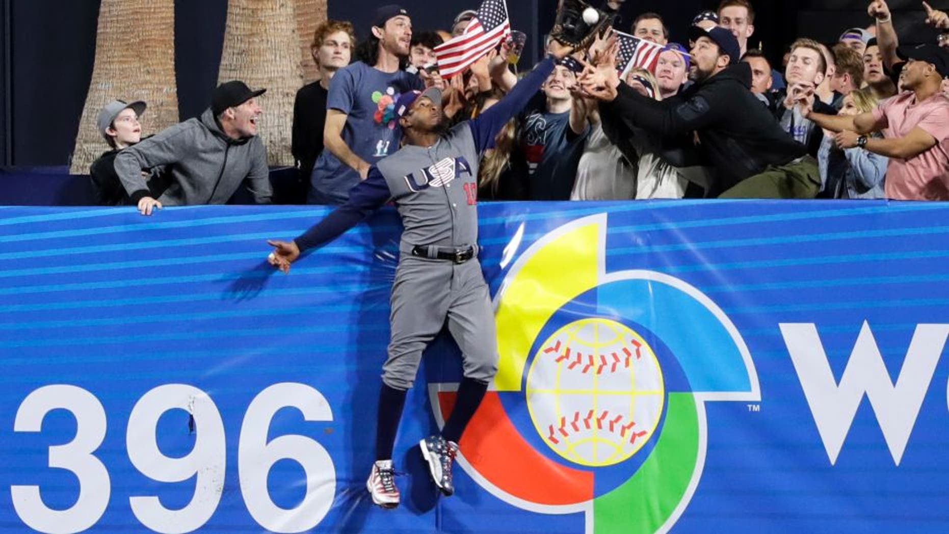 U.S. outfielder Adam Jones grabs a catch above the wall for the out on the Dominican Republic's Manny Machado during the seventh inning of a second-round World Baseball Classic baseball game Saturday, March 18, 2017, in San Diego. (AP Photo/Gregory Bull)