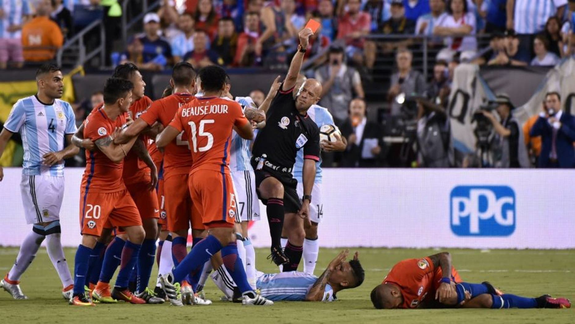 Brazilian referee Heber Lopes red-cards Argentina's Marcos Rojo (C on the ground) for fouling Chile's Arturo Vidal (R on the ground) the Copa America Centenario final in East Rutherford, New Jersey, United States, on June 26, 2016. / AFP / Nelson ALMEIDA (Photo credit should read NELSON ALMEIDA/AFP/Getty Images)