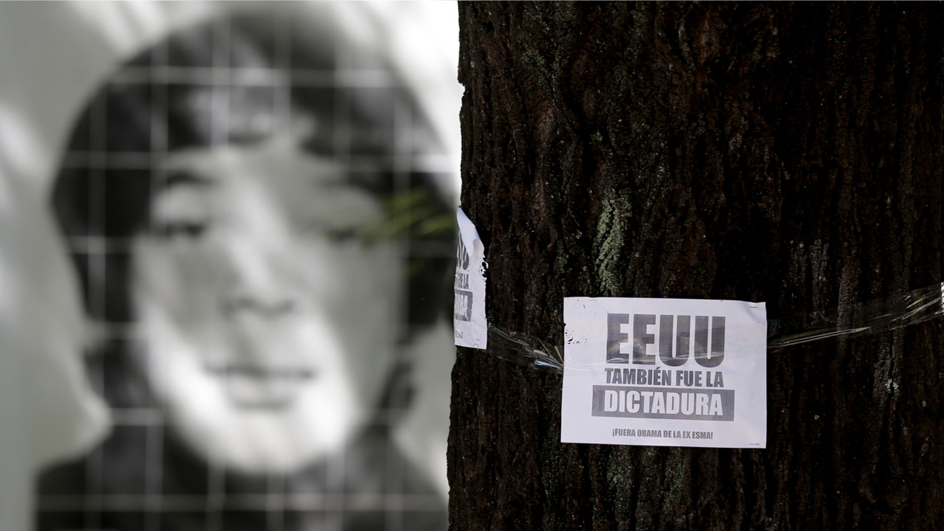 March 16, 2016: A picture of a person that was disappeared during Argentina's military dictatorship is seen behind a leaflet on a tree that reads in Spanish "The U.S. was also the dictatorship, Obama out of former Argentine Navy School of Mechanics" at the Space for Memory and for the Promotion and Defense of Human Rights in Buenos Aires. (AP Photo/Natacha Pisarenko)