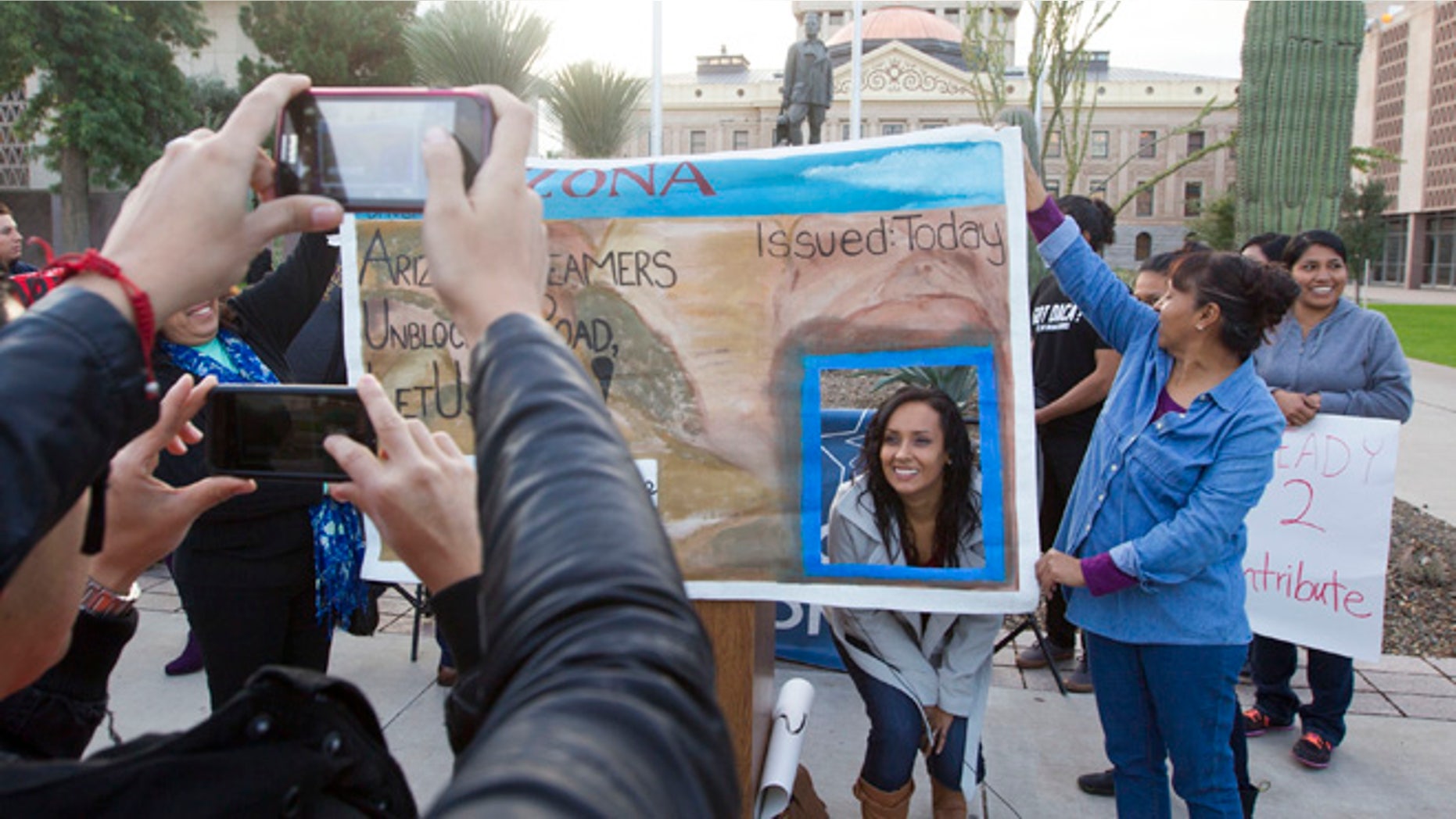 FILE - In this Dec 17, 2014, file photo, Erika Andiola gets her photo taken at the Arizona State Capitol in Phoenix, as thousands of young immigrants moved a step closer to getting driver's licenses in Arizona. A single mother battling cancer and a victim of domestic abuse are among the immigrants who qualify for Arizona driver's licenses but have been illegally denied the chance to drive a car, a group of advocacy organizations said in a new federal lawsuit. Denying licenses to some immigrants in the country illegally who have been granted deferred action, or protection from deportation, is unconstitutional, according to the claim filed Monday, Sept. 12, 2016 by the Mexican American Legal Defense and Educational Fund, the National Immigration Law Center and the Ortega Law Firm.(Nick Oza /The Arizona Republic via AP, File)