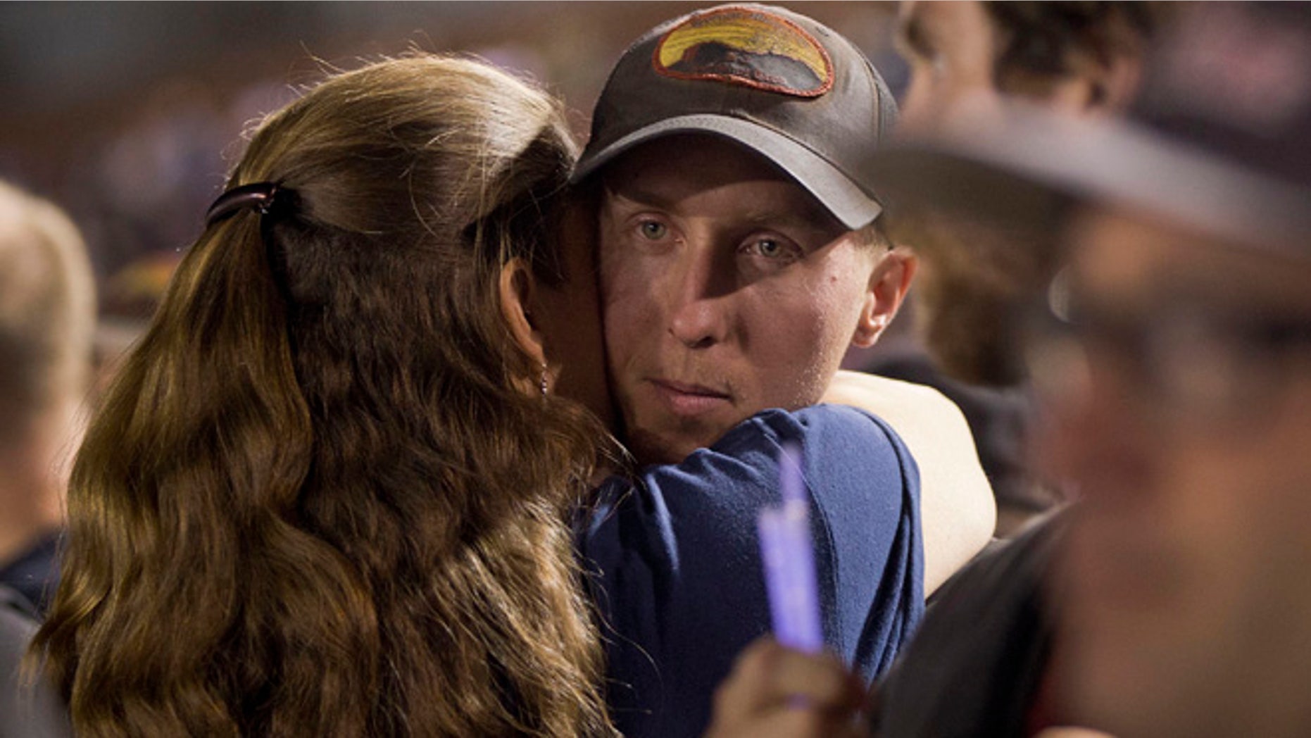 In this July 2, 2013 file photo, firefighter Brendan McDonough embraces a mourner near the end of a candlelight vigil in Prescott, Ariz. McDonough was the sole survivor of the 20-man Granite Mountain Hotshot Crew after an out-of-control blaze killed the 19 near Yarnell, Ariz. Investigators are set to release a report Saturday, Sept. 28, 2013, on the deaths of the 19 elite firefighters who became trapped by flames in a brush-choked canyon north of Phoenix.