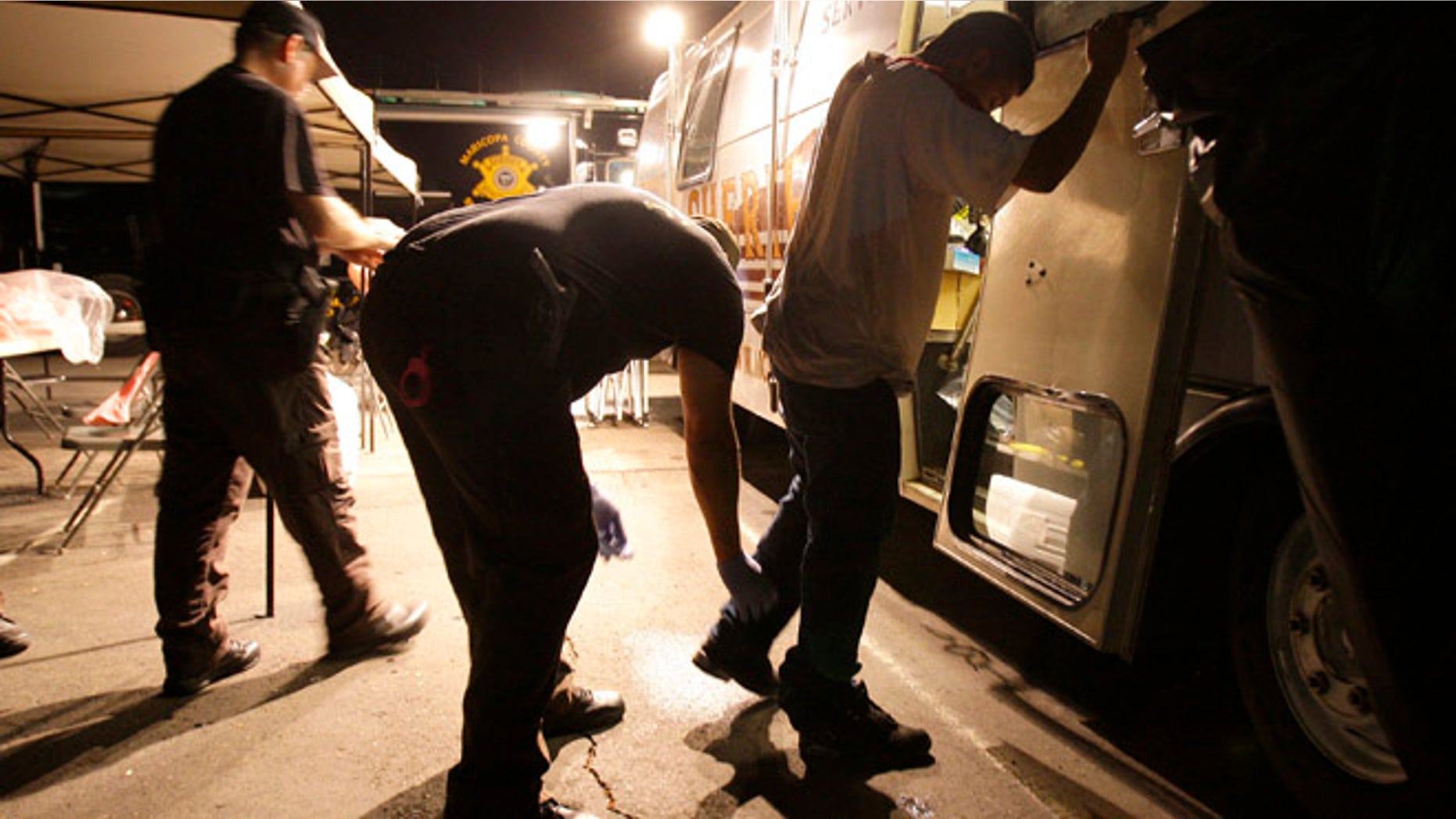 FILE - In this July 29, 2010 file photo, Maricopa County Sheriff's deputies, left, check the shoes of a suspect arrested during a crime suppression sweep in Phoenix. A judge in Arizona on Tuesday, Sept. 18, 2012 ruled that police can immediately start enforcing the most contentious section of the state's immigration law, marking the first time officers can carry out the so-called "show me your papers" provision. (AP Photo/Ross D. Franklin, File)