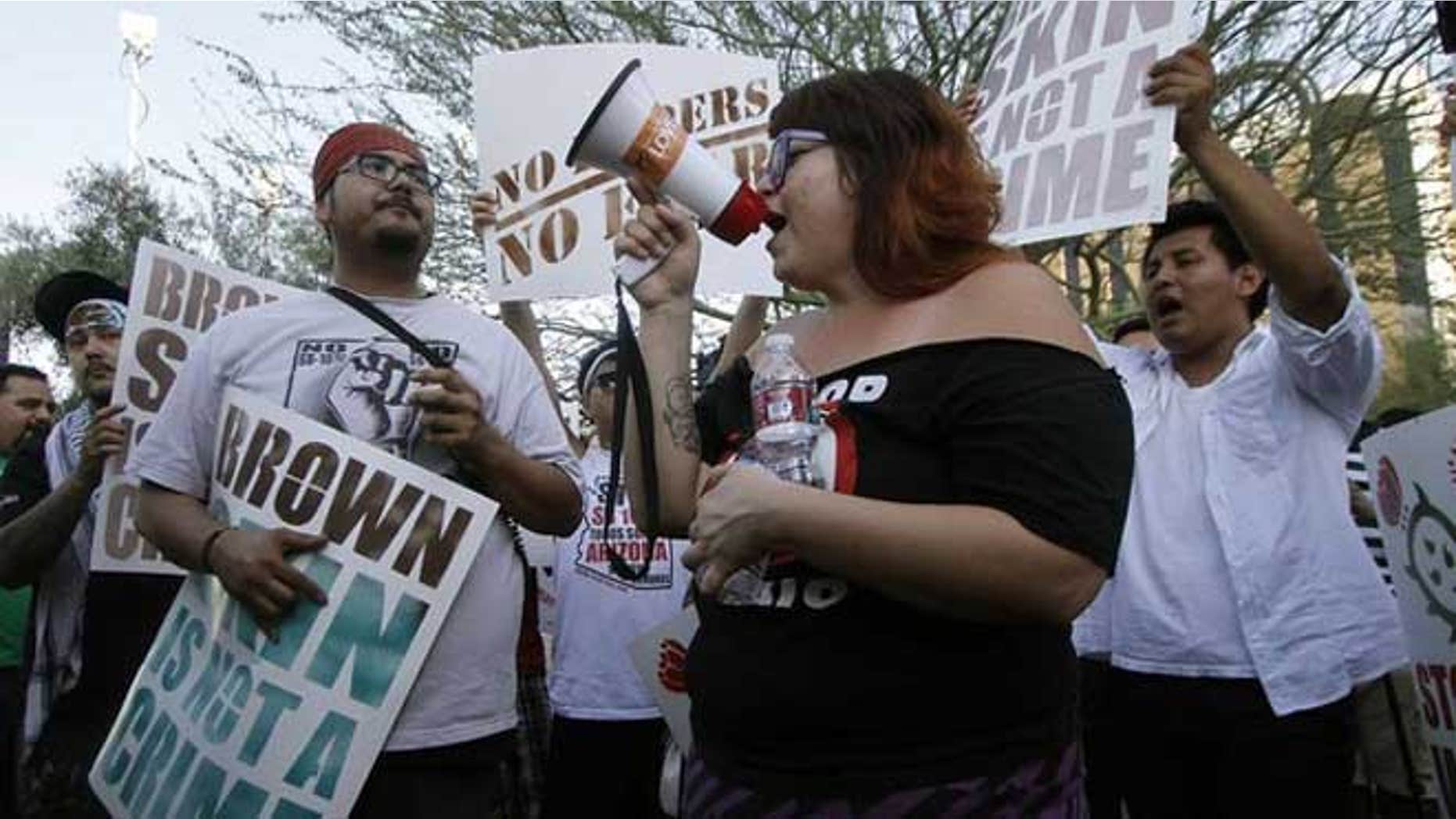 June 25, 2012: People hold signs as they gather during a protest in front of the Immigration and Customs Enforcement offices in Phoenix, Arizona.