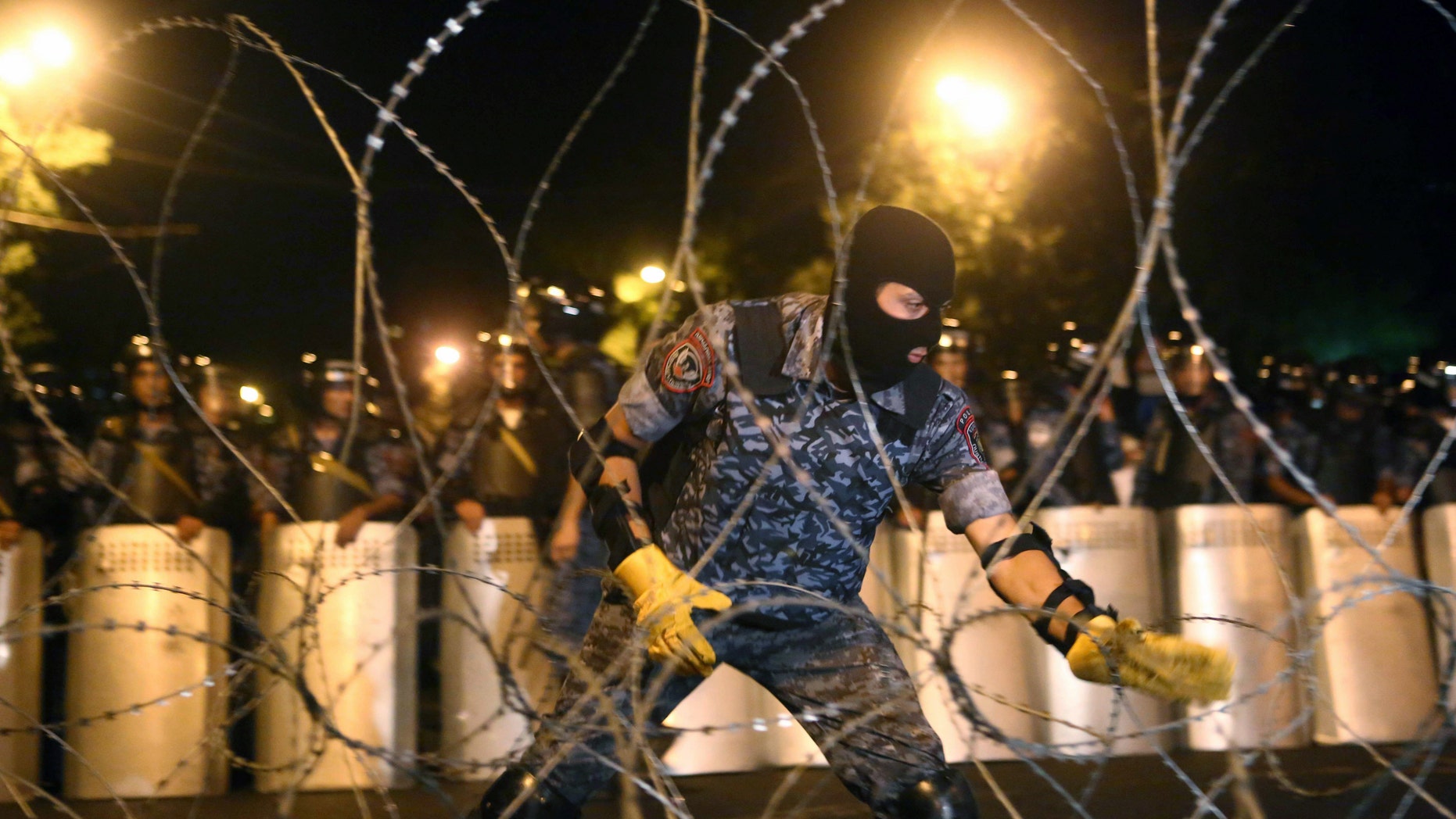 A riot police officer installs barbed wire during an anti-government march in Armenia.
