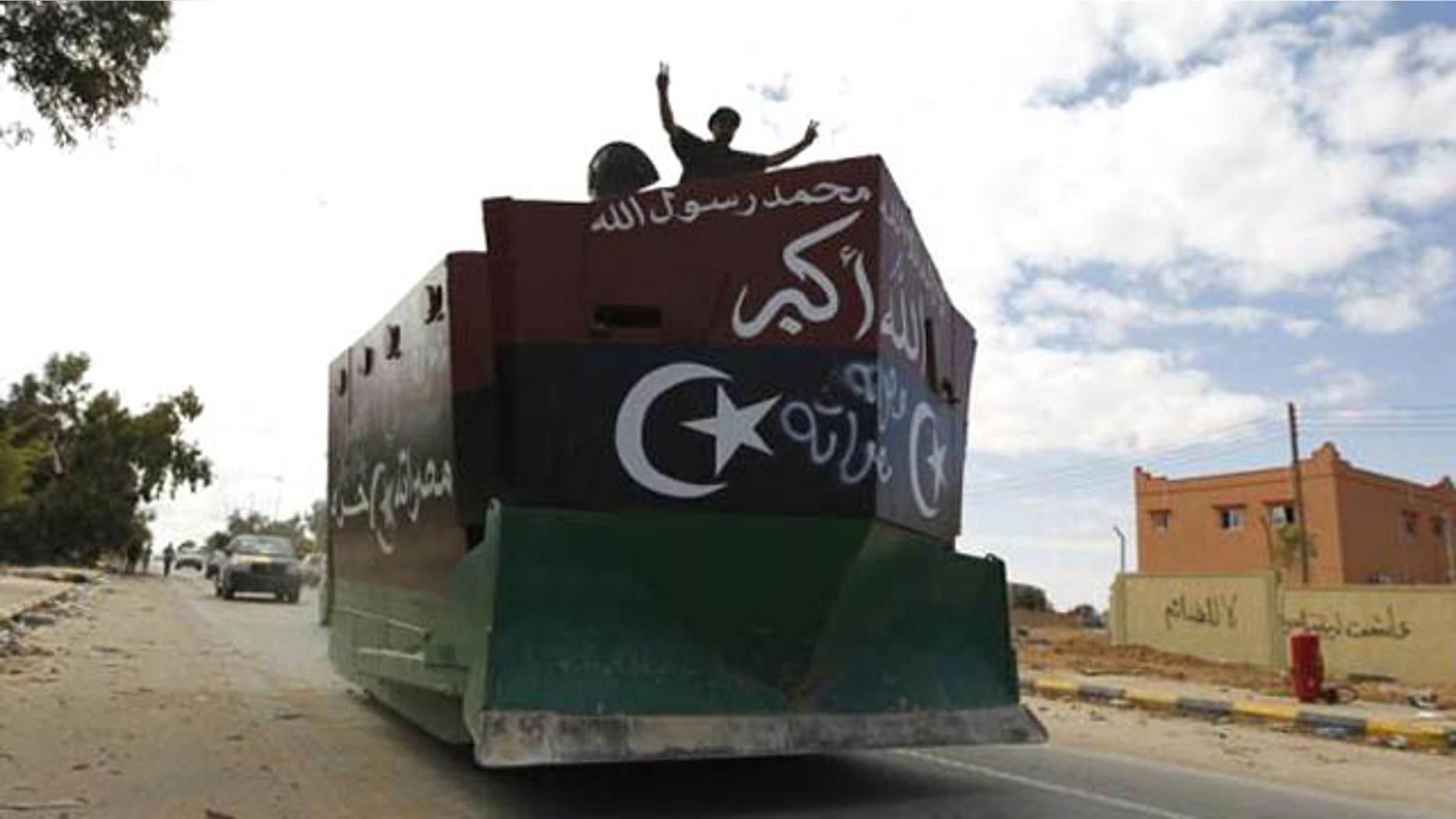 Oct. 19, 2011: An anti-Gaddafi fighter flashes victory signs on an armored bulldozer during violent clashes with pro-Gaddafi forces at the frontline in center Sirte.