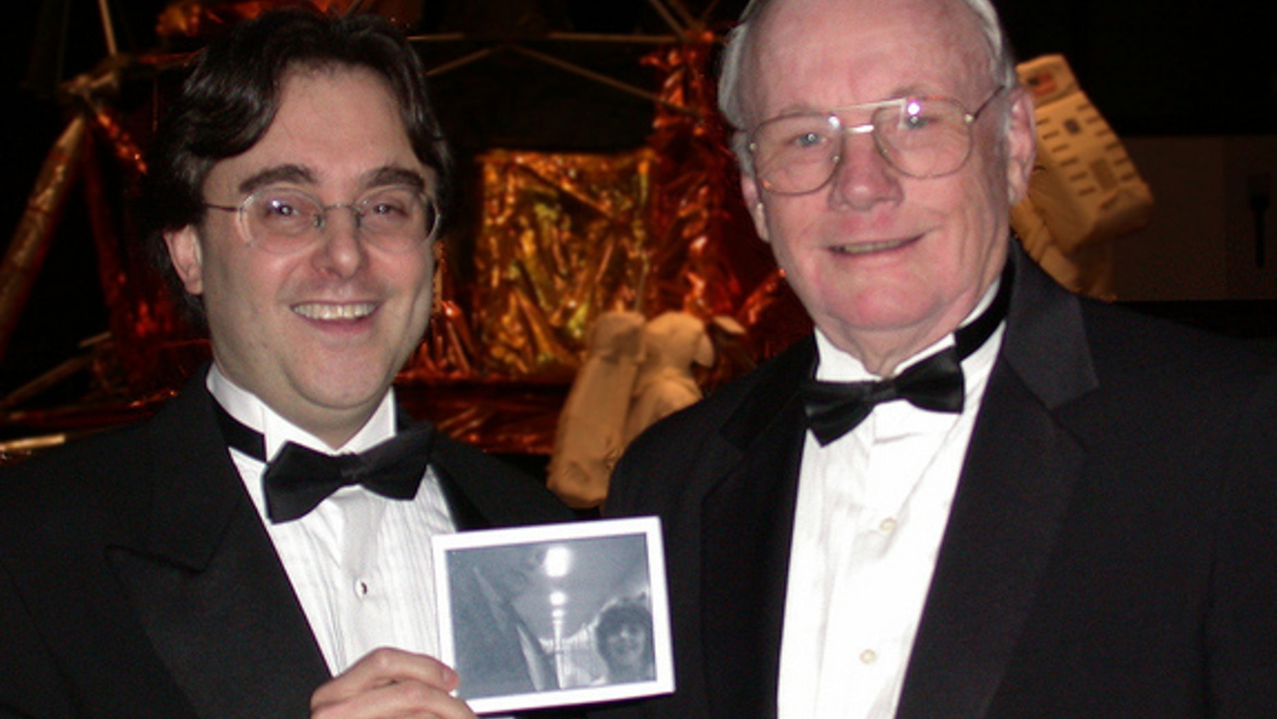 Space writer Andrew Chaikin poses for a photo with Neil Armstrong, the first person to walk on the moon, during a 2002 at an Apollo anniversary event at the Smithsonian National Air & Space Museum. Chaikin is holding photo of the duo taken by A