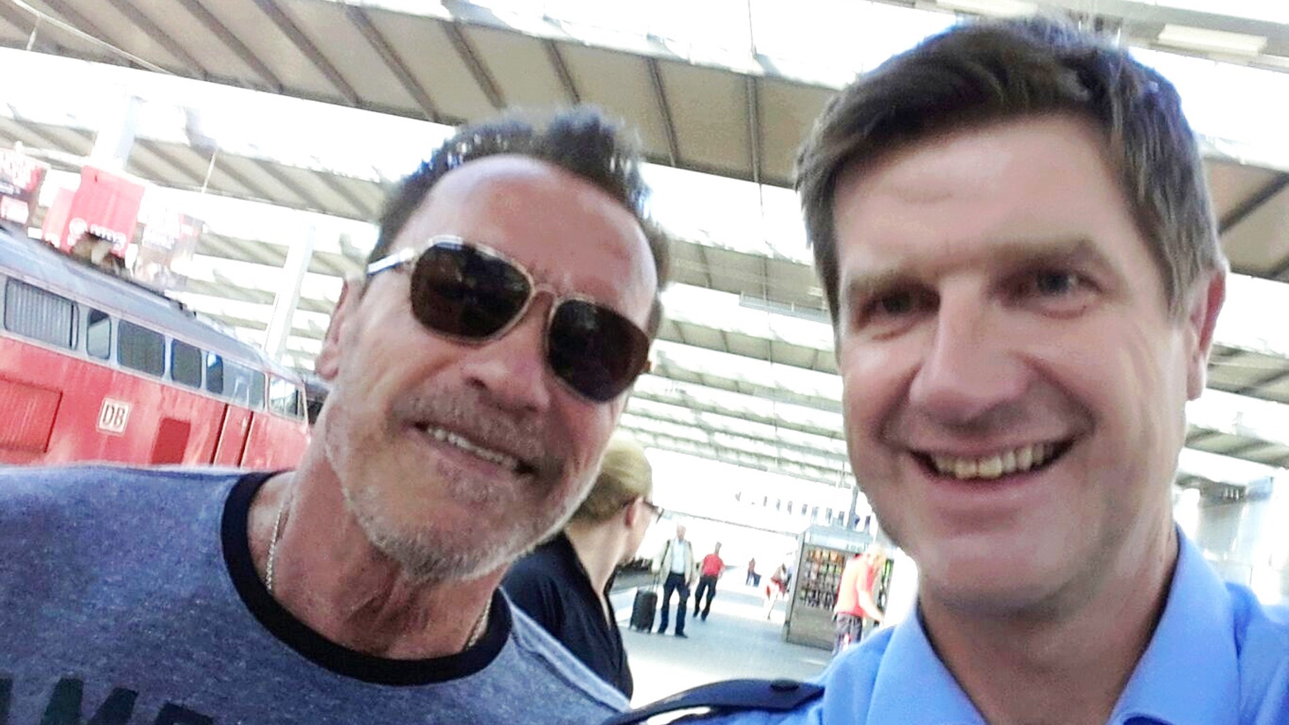 Arnold Schwarzenegger poses with Munich police officer Stefan Schmitt after being stopped for cycling too fast in a Munich train station.