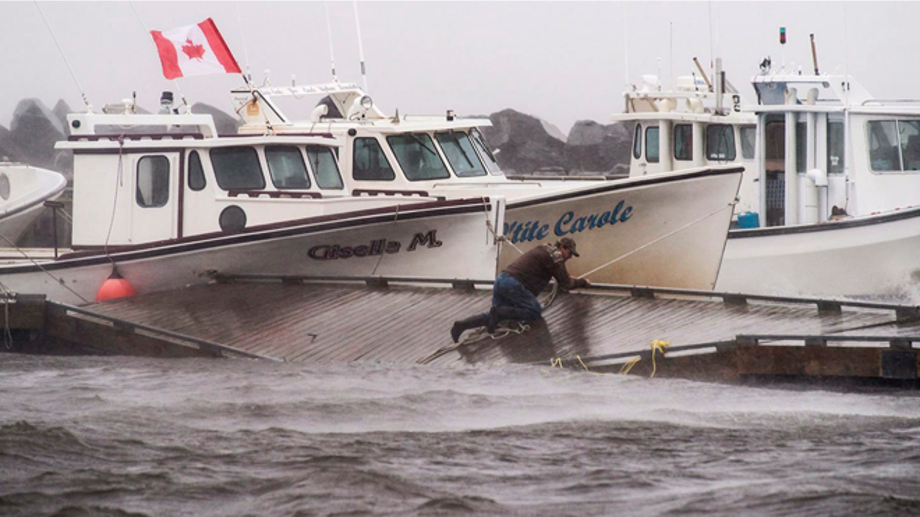 July 5, 2014: A lobster fisherman slips but holds on while trying to secure lines to his fishing boat after the floating dock broke apart during tropical storm Arthur in Escuminac, New Brunswick. (AP)