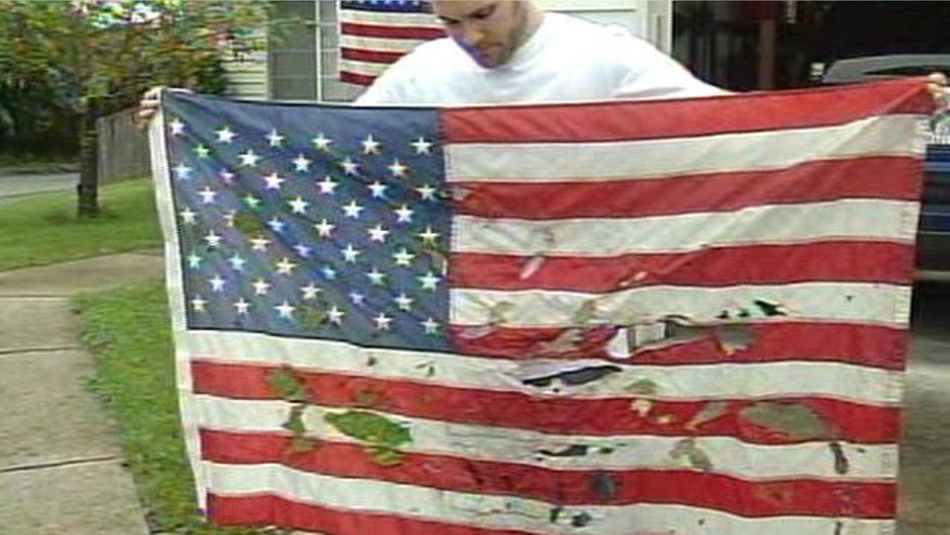 Christian Ashby, of Portland, Ore., holds an American flag that was vandalized outside of his home sometime late Saturday or early Sunday.