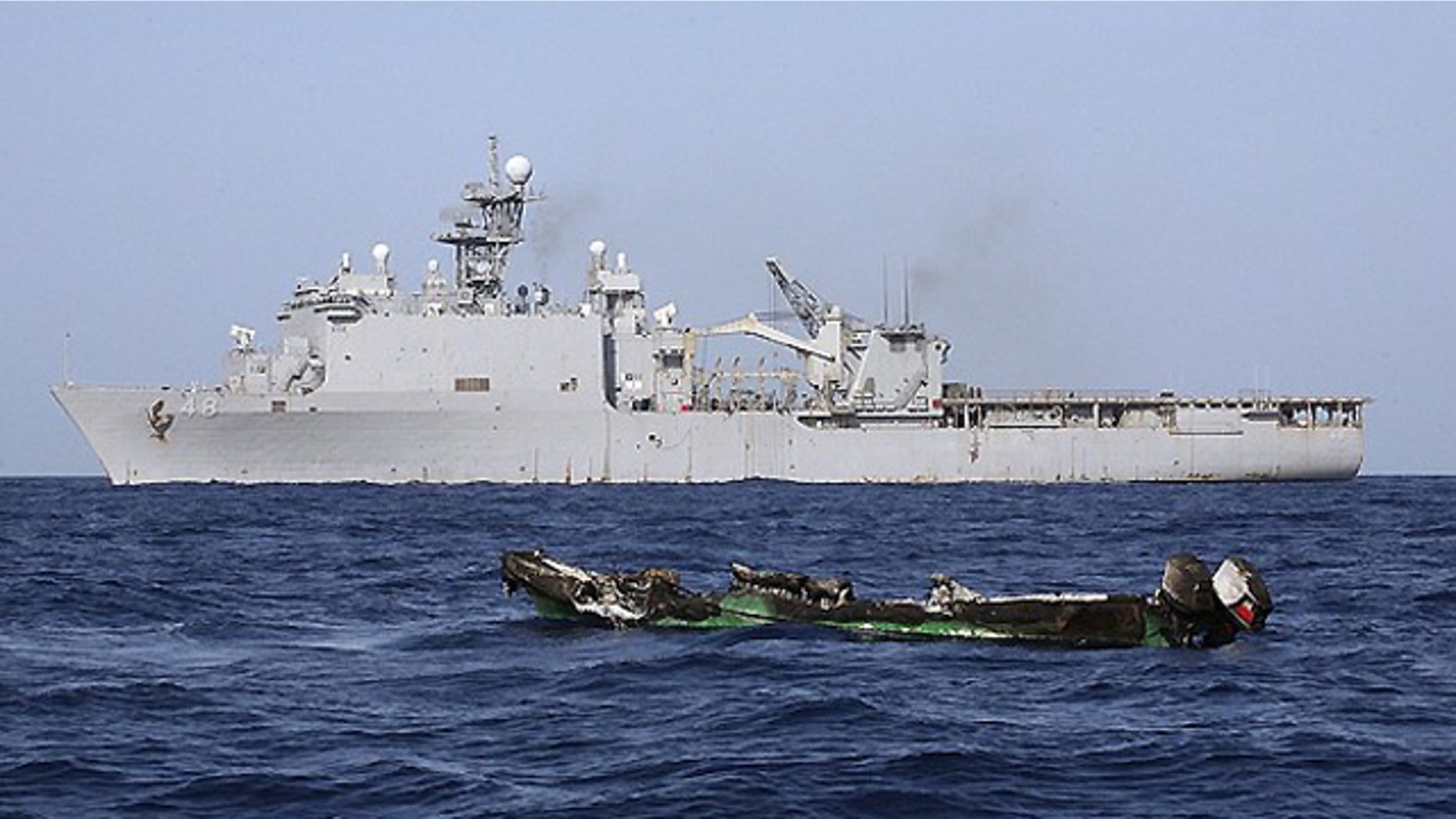 April 10, 2010: The burned out hull of a suspected pirate skiff drifts in the Gulf of Aden in front of the USS Ashland. (Reuters)