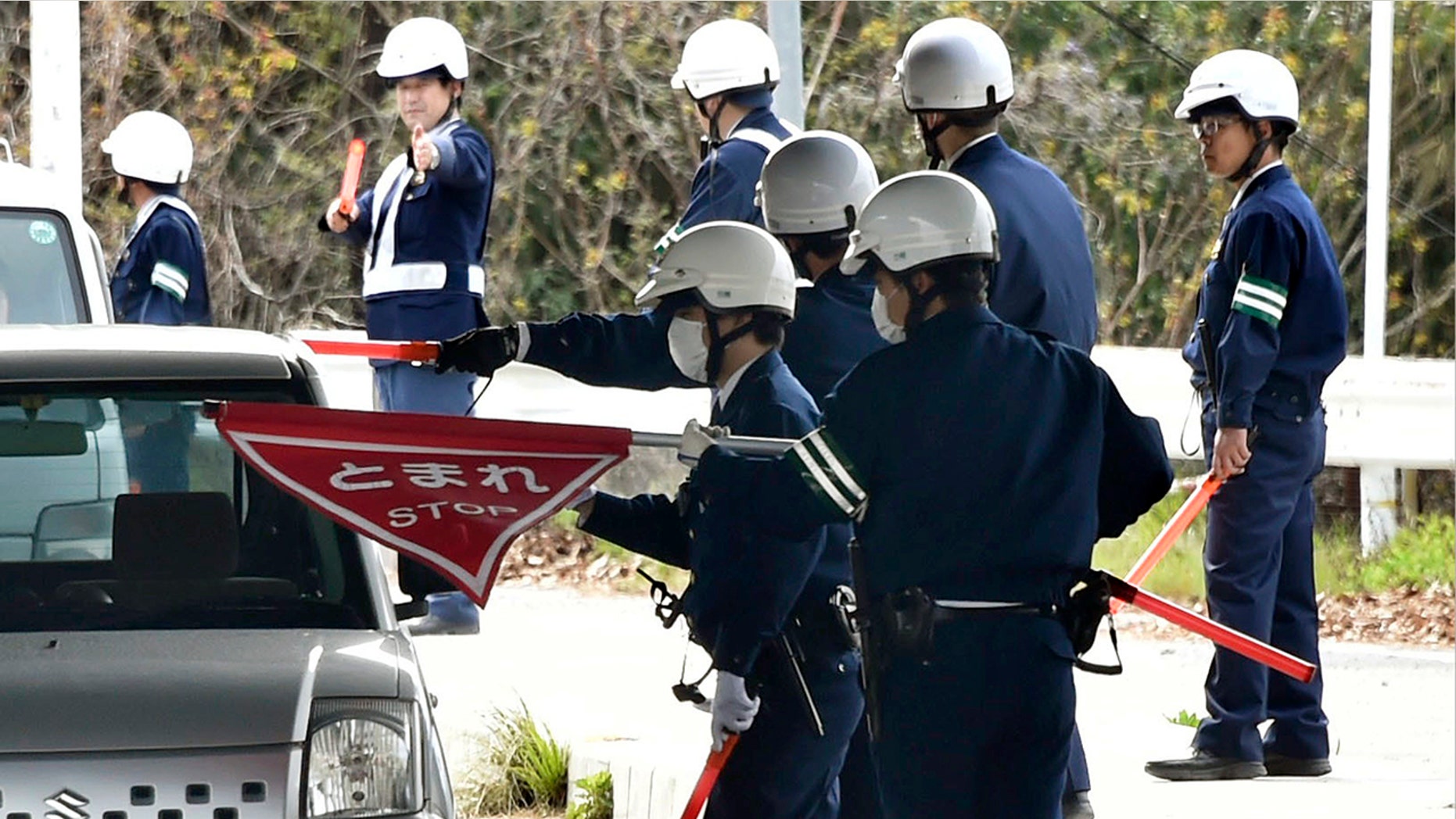 In this April 11, 2018, photo, police officers inspect cars at a checkpoint in Onomichi, Hiroshima prefecture.
